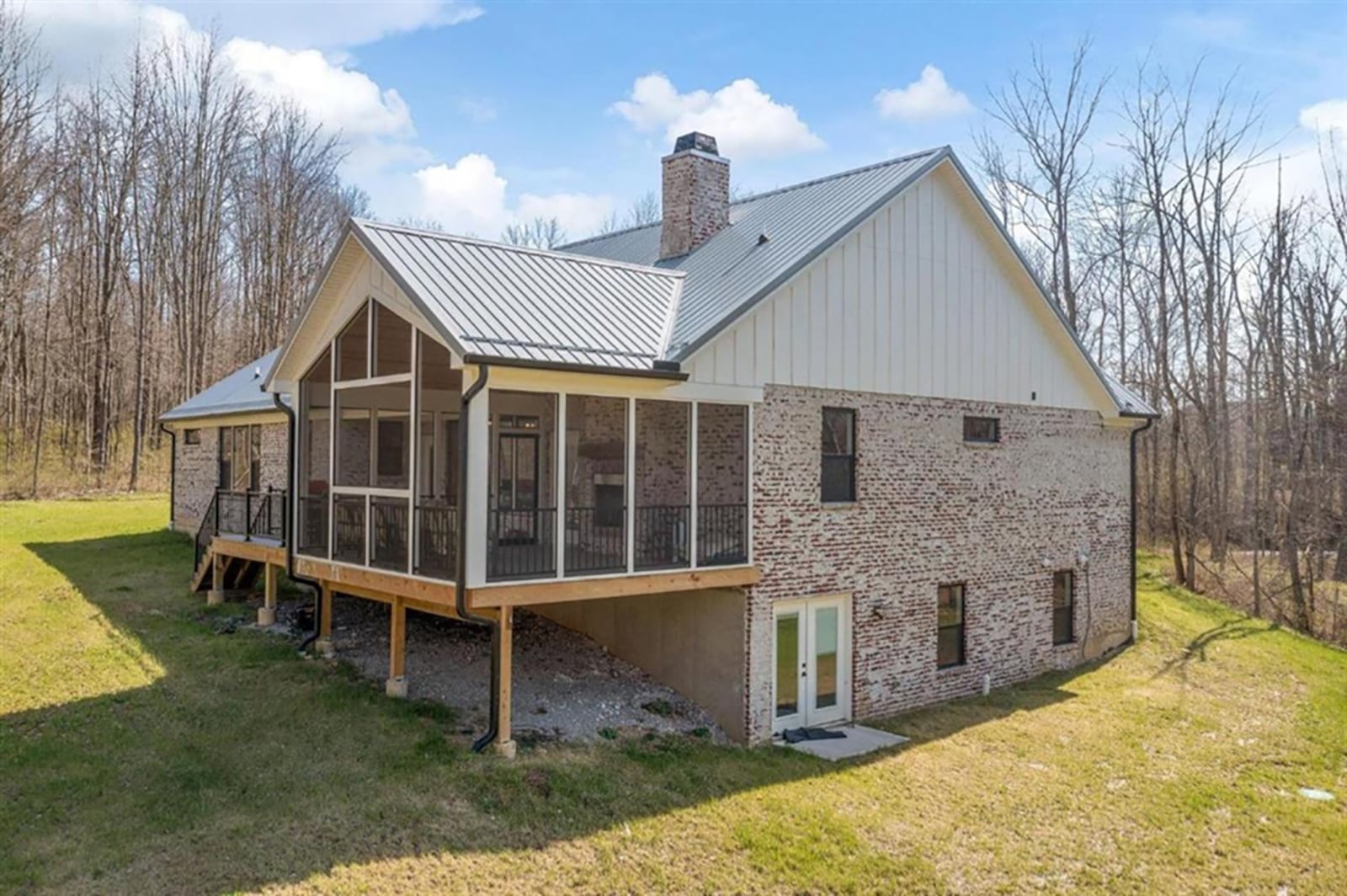 Triple picture windows look out over the back yard and are flanked by glass doors. One door opens to a covered balcony porch, and the other into screen-enclosed porch with a wood cathedral ceiling and wood-burning fireplace. Both the porch and balcony have access to the back yard. CONTRIBUTED PHOTO