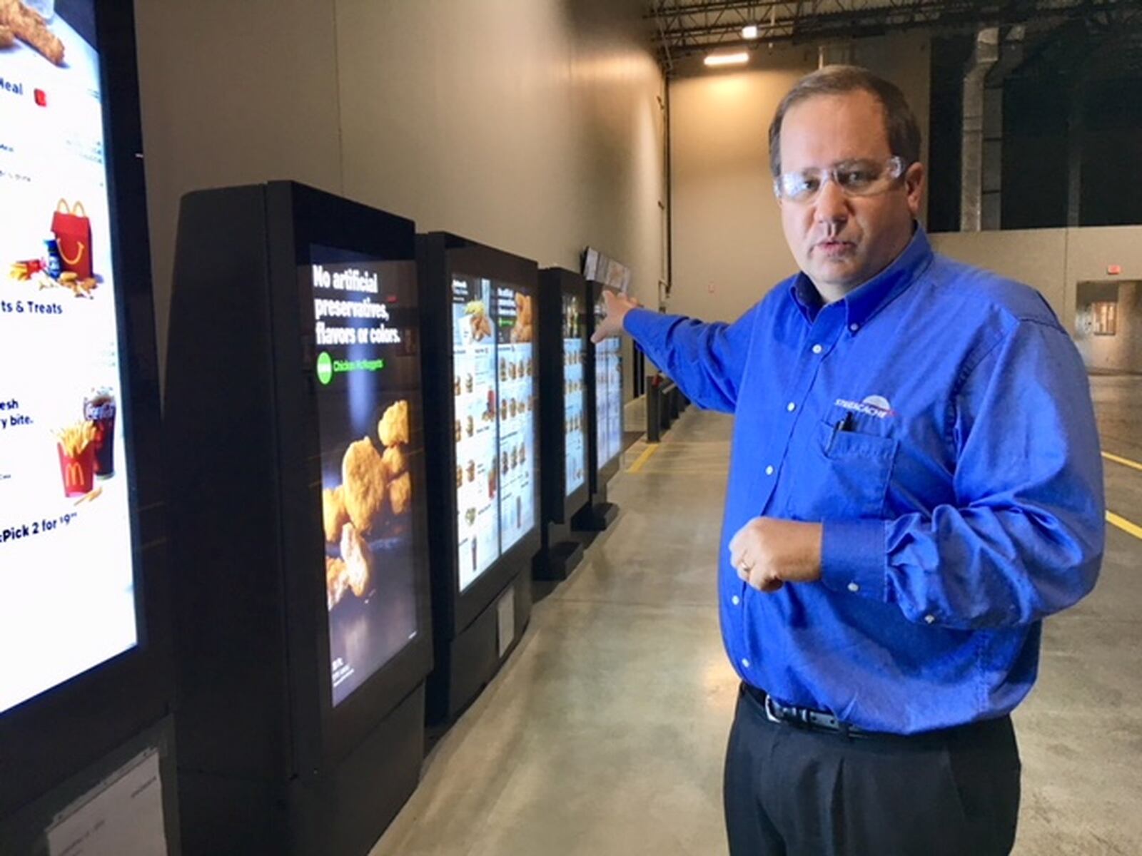 Chris Riegel, founder and chief executive of Stratacache, runs a company based in Dayton but increasingly busy in a part of the globe that has two-thirds of the world’s population. In this 2018 photo, he shows an array of the company’s digital menu displays in the company's Trotwood facility. THOMAS GNAU/STAFF