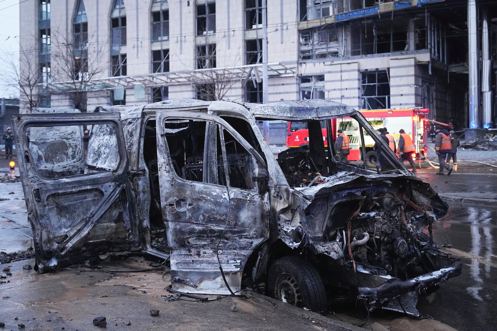 A destroyed car is seen as firefighters work on the site of a damaged building after a Russian missile attack in Kyiv, Ukraine, Saturday, Jan. 18, 2025. (AP Photo/Efrem Lukatsky)