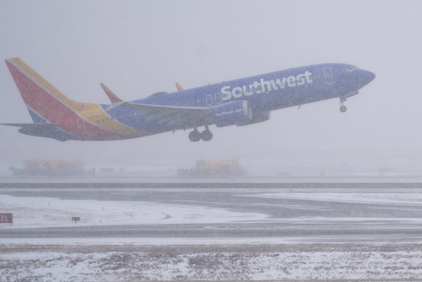 A Southwest Airlines plane takes off as the snow plows clear runways afar Friday, Jan 10, 2025, in Nashville, Tenn. (AP Photo/George Walker IV)