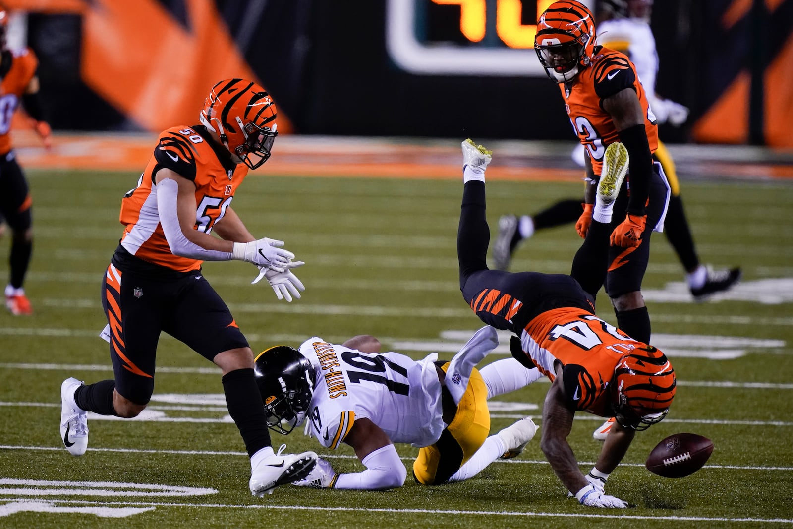 Cincinnati Bengals' Vonn Bell (24) and Jordan Evans (50) look to recover a fumble by Pittsburgh Steelers' JuJu Smith-Schuster (19) during the first half of an NFL football game, Monday, Dec. 21, 2020, in Cincinnati. (AP Photo/Bryan Woolston)