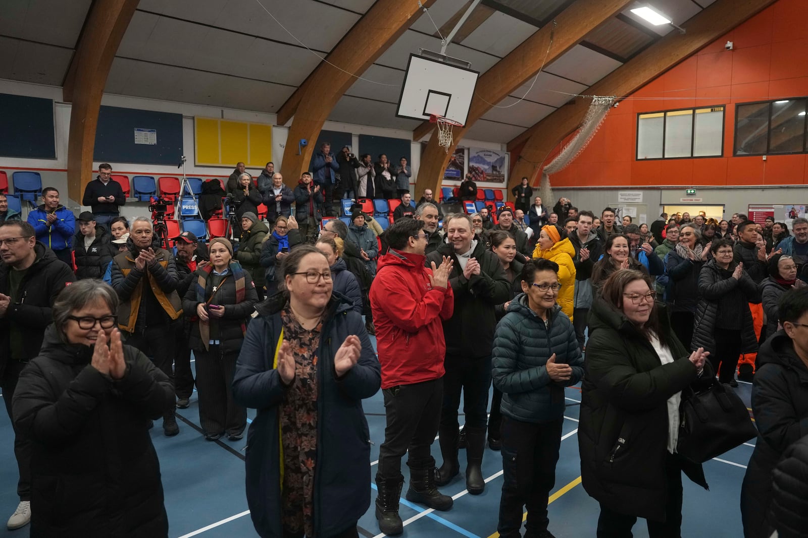 People applaud as the polls open for people to cast their vote in parliamentary elections, in Nuuk, Greenland, Tuesday, March 11, 2025. (AP Photo/Evgeniy Maloletka)