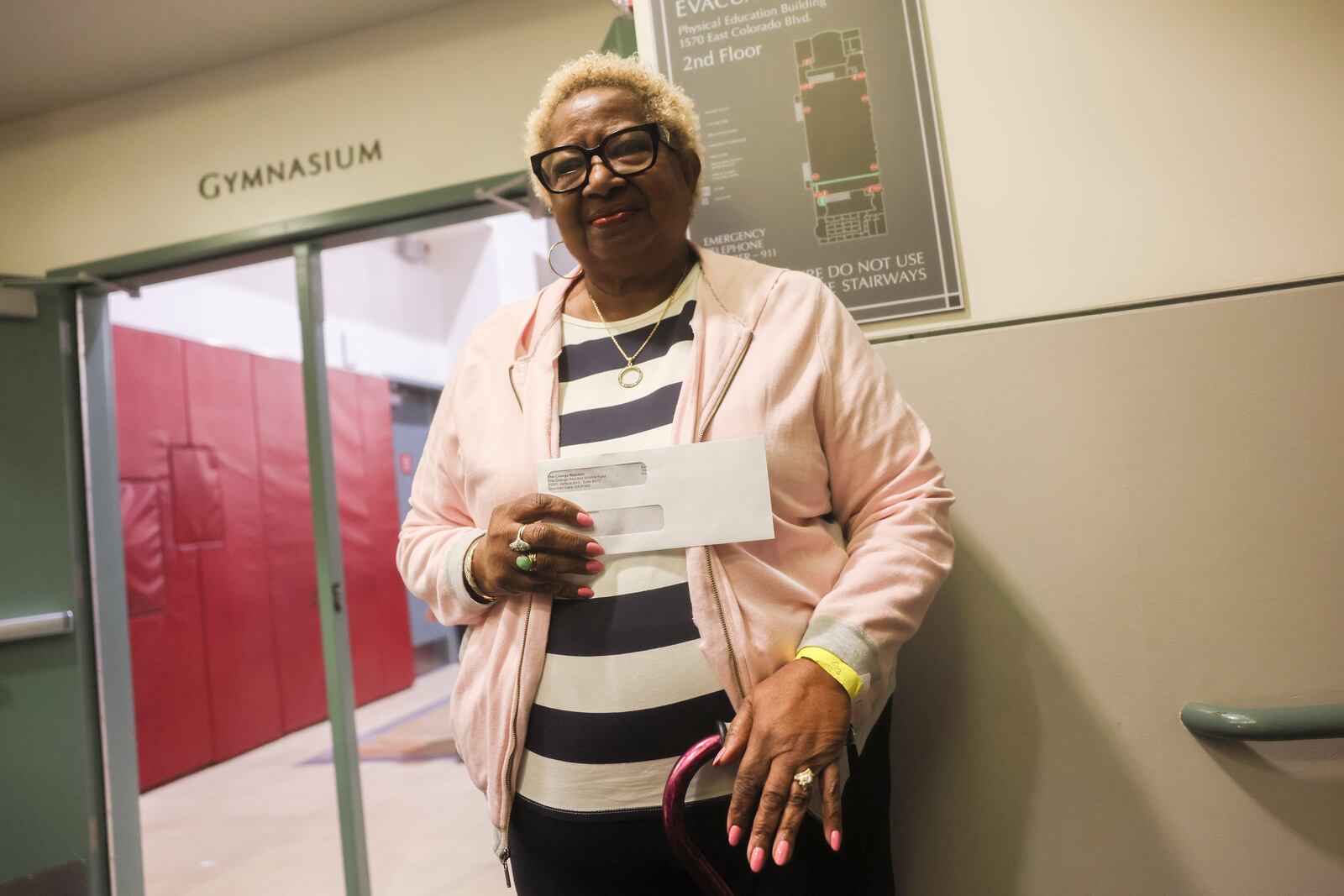 Impacted by the Eaton Fire, Katherine Anderson poses with an envelope containing a check as she leaves the gymnasium of Pasadena City College where The Change Reaction is handing out about 1,000 checks of between $2,500-$5,000 to people impacted by the wildfire, Tuesday, Jan. 28, 2025 in Pasadena, Calif. (AP Photo/Etienne Laurent)