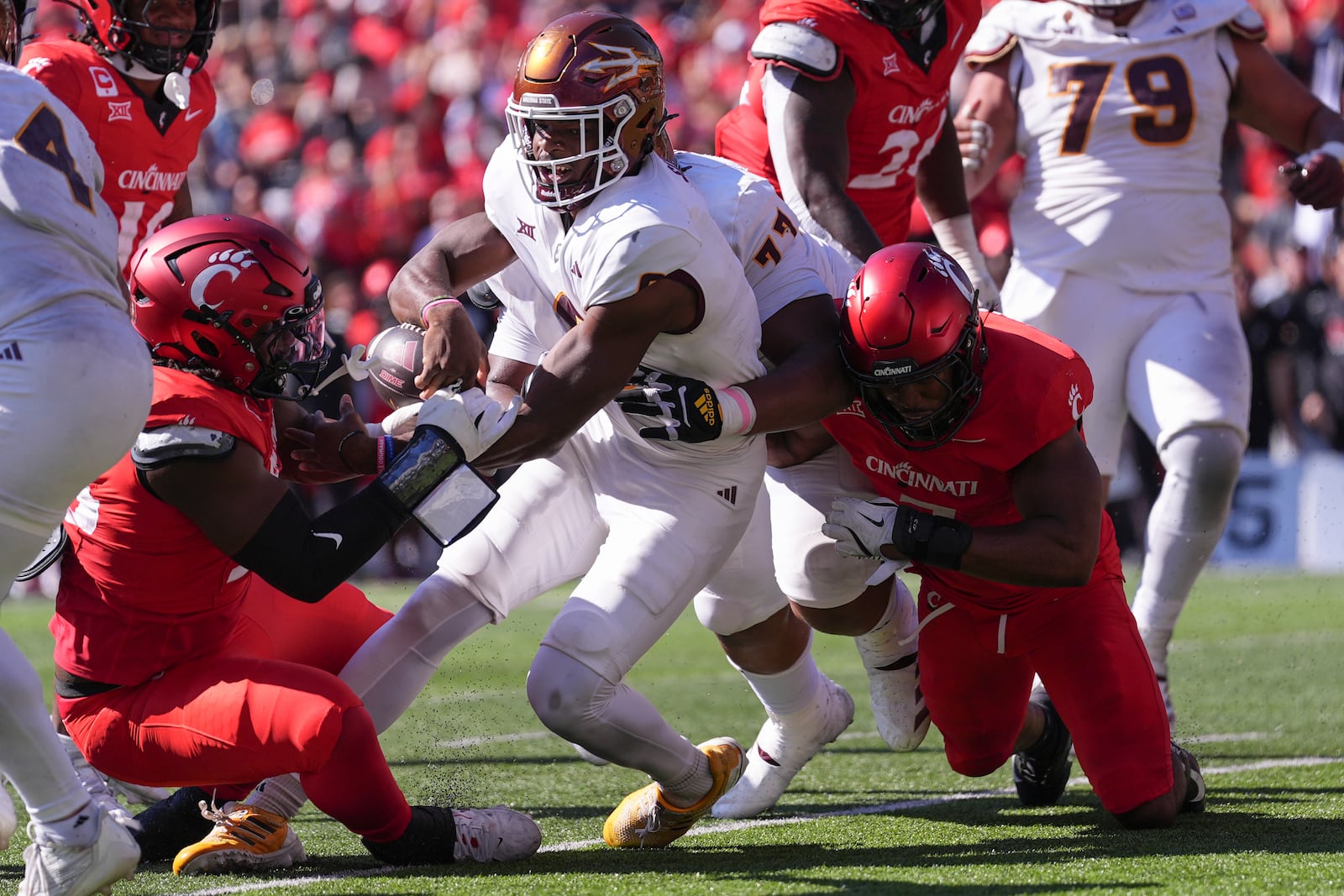 Arizona State's Jeff Sims, center, nearly fumbles the ball on a carry during the first half of an NCAA college football game against Cincinnati, Saturday, Oct. 19, 2024, in Cincinnati. (AP Photo/Kareem Elgazzar)