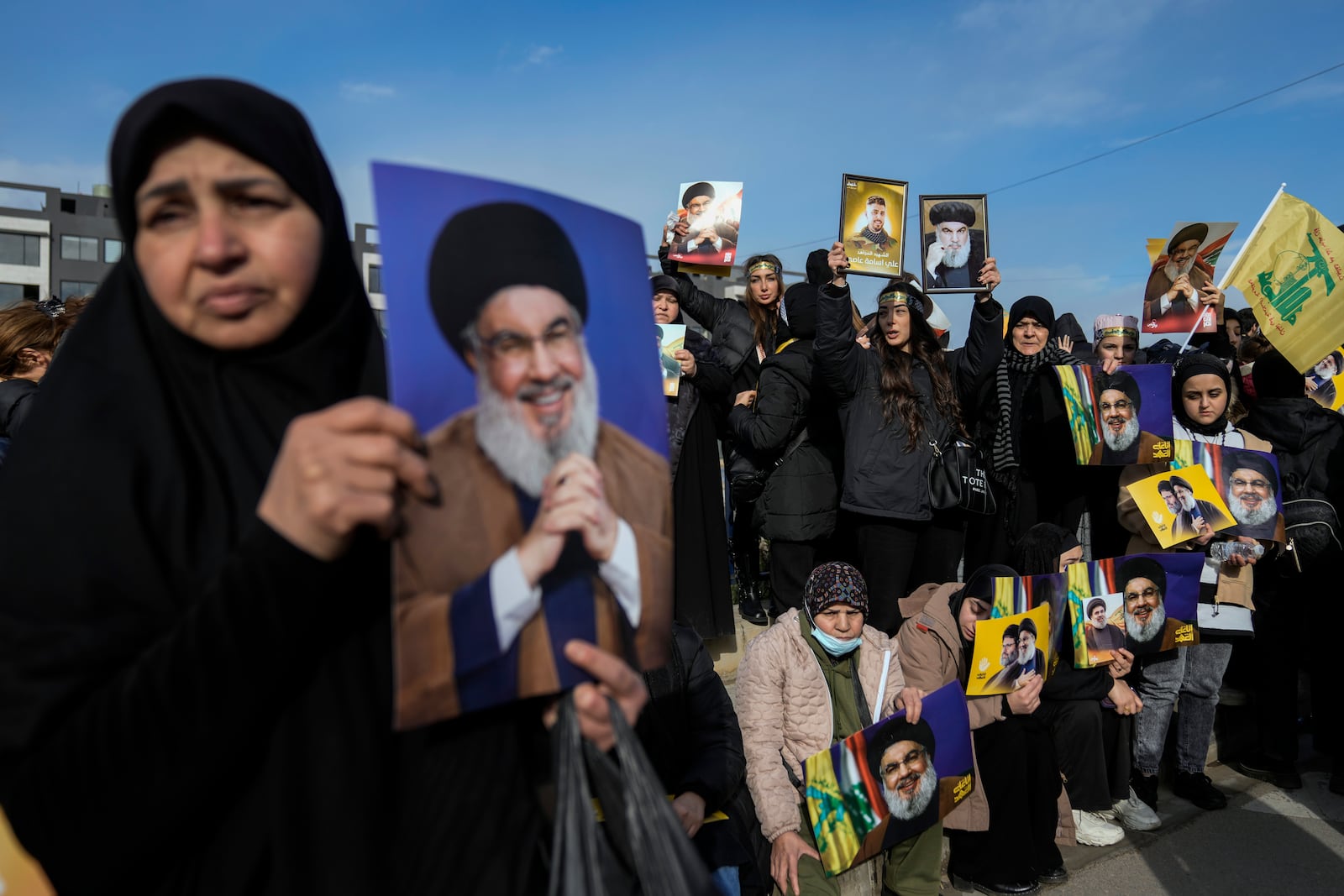 Mourners hold pictures of Lebanon's former Hezbollah leaders, Hassan Nasrallah and Hashem Safieddine, as they gather along a highway to attend their funeral procession in Beirut, Lebanon, Sunday Feb. 23, 2025. (AP Photo/Bilal Hussein)