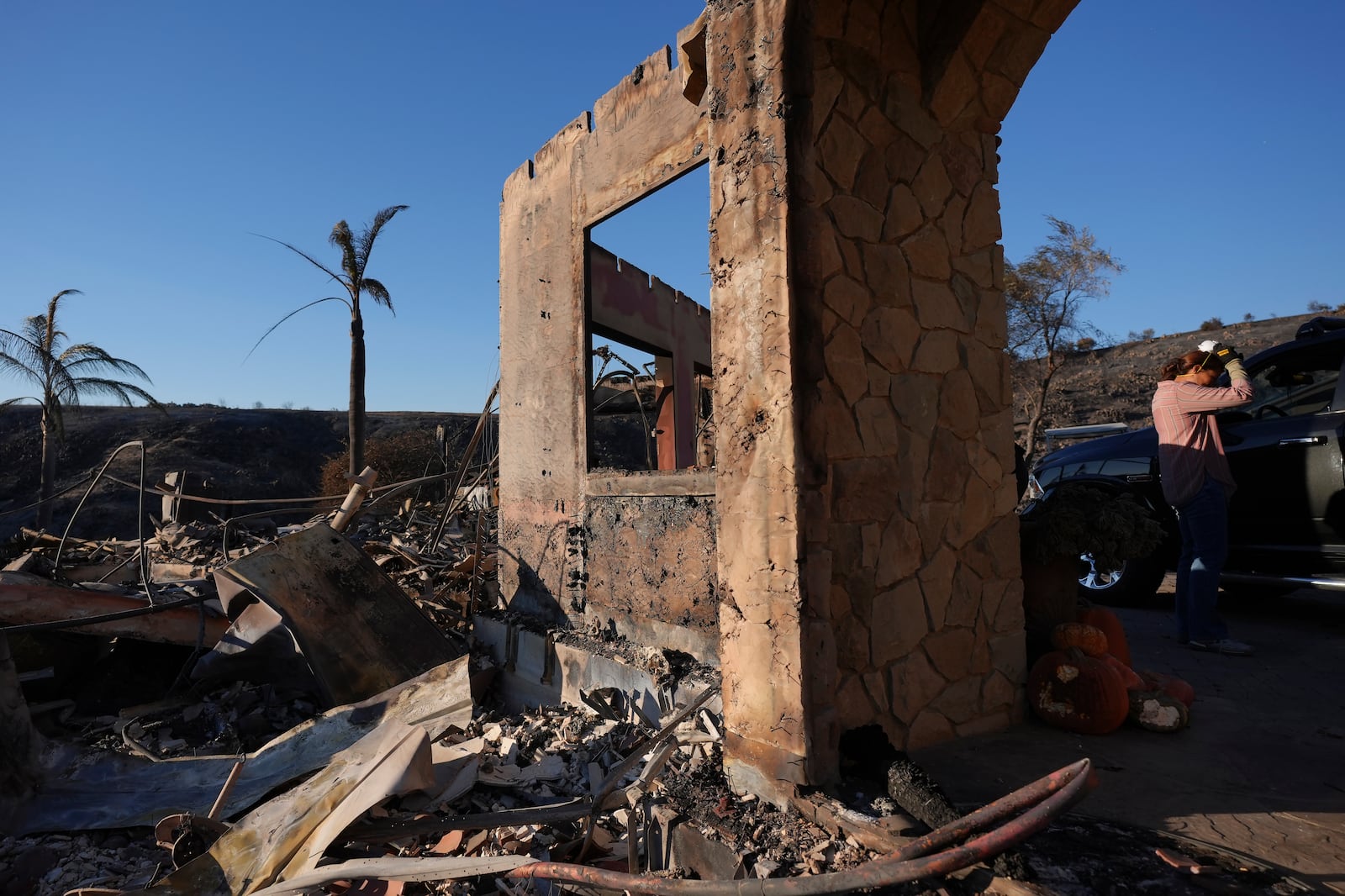 Heidi Nardoni, right, and family friends search her home destroyed by the Mountain Fire in Camarillo, Calif., Friday, Nov. 8, 2024. (AP Photo/Jae C. Hong)