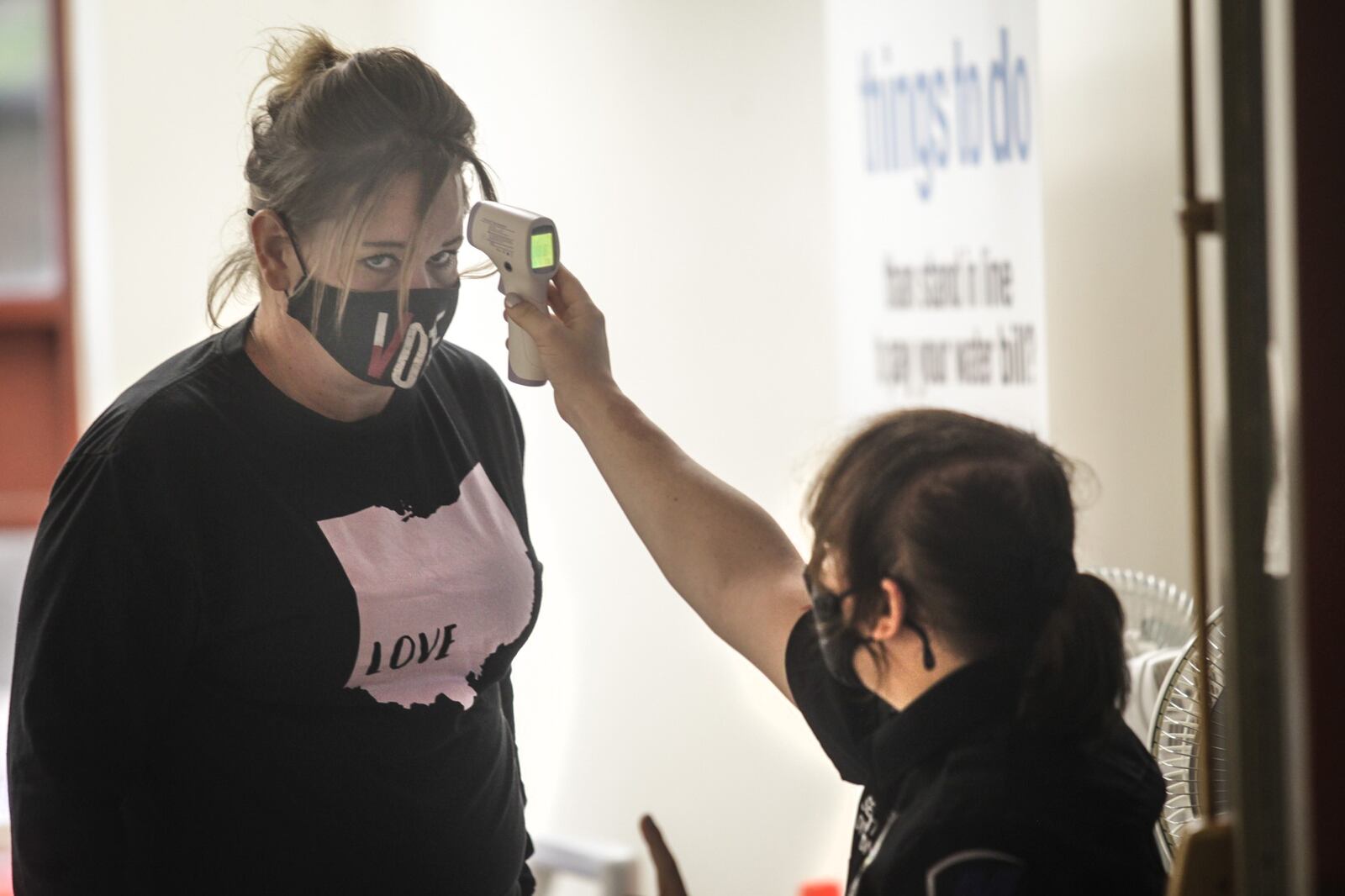 Security guard at City Hall, Lilith York checks the temperature of Lisa Antrican as she enters the building on Ludlow St. to pay her water bill Thursday October 1, 2020.