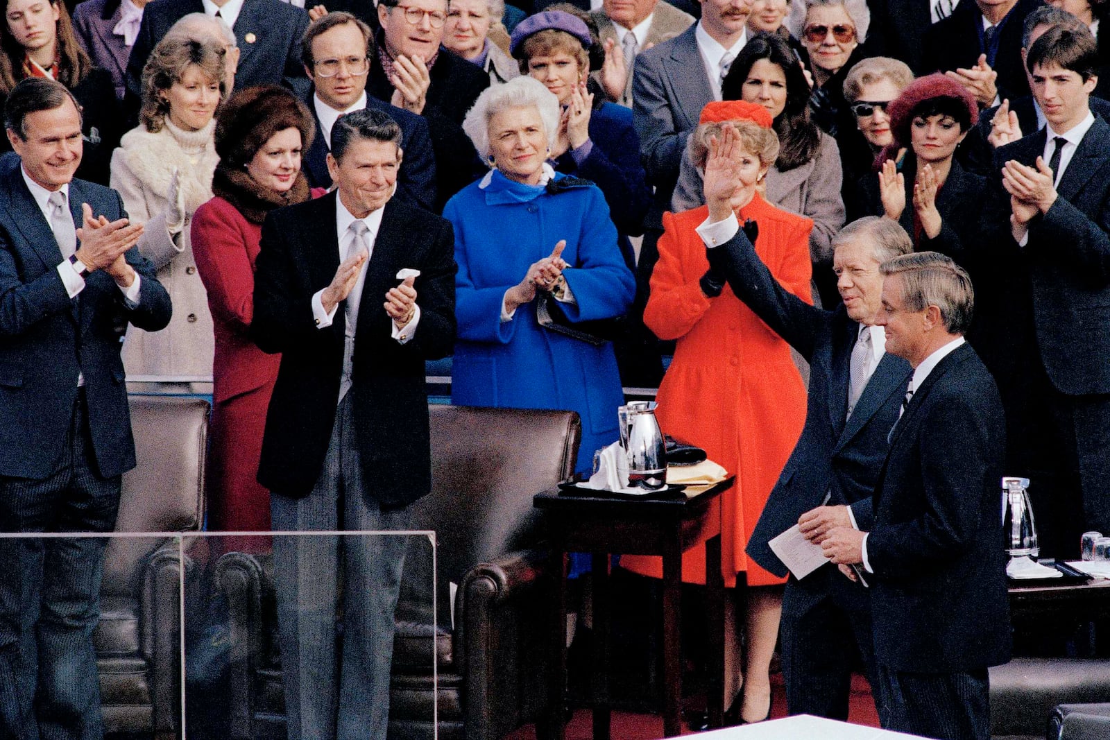 FILE - Outgoing President Jimmy Carter waves to the crowd at the inauguration of 40th President Ronald Reagan in Washington, Jan. 20, 1981. In the background, new Vice President George Bush, Reagan, Barbara Bush and first lady Nancy Reagan applaud. Next to Carter is outgoing Vice President Walter Mondale, and at far right, Reagan's son Ron applauds. (AP Photo, File)