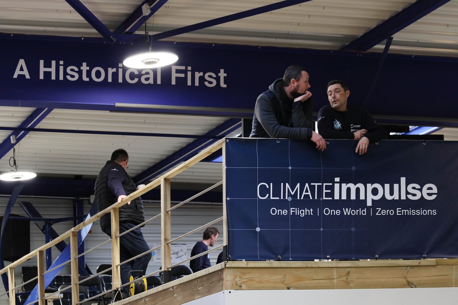 Employees gather at a press event for the Climate Impulse, a plane powered by liquid hydrogen, in a hangar in Les Sables d'Olonne, France on Thursday, Feb. 13, 2025.(AP Photo/Yohan Bonnet)