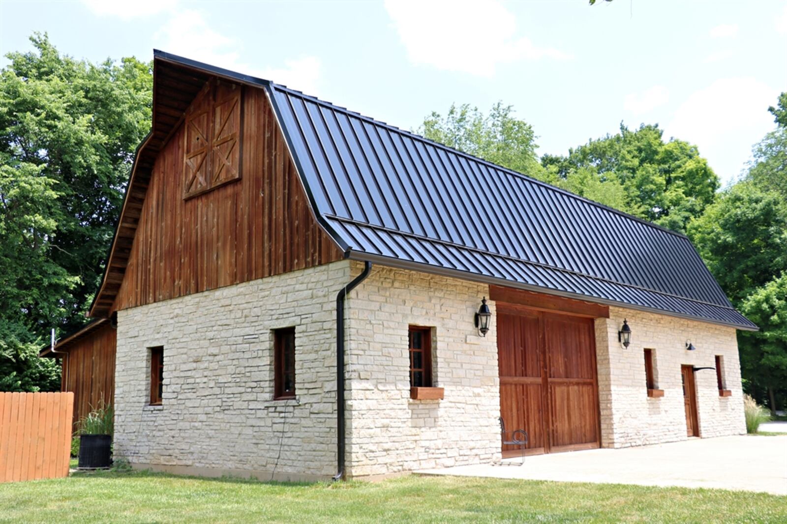 The 60-by-25-foot barn has a stone exterior with a metal roof. An oversized overhead door allows for recreational and multiple vehicle storage; and a single door allows entry into a possible workshop or office space.