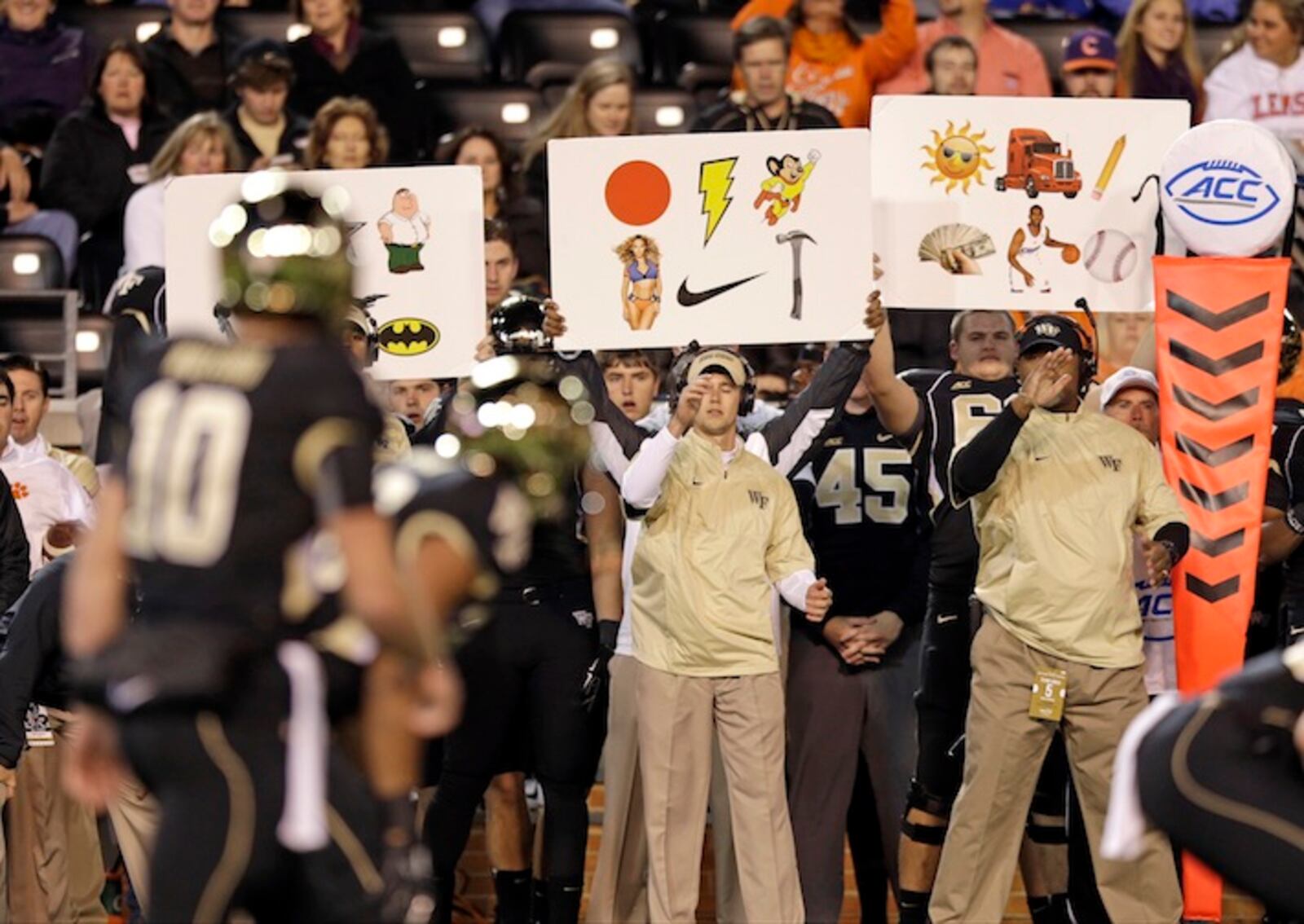 FILE - In this Nov. 6, 2014, file photo, Wake Forest coaches use signs to signal in a play during the first half of an NCAA college football game against Clemson in Winston-Salem, N.C. Once a technique used to replace hand signals for offenses, in the past few years, defenses have started using them, too. (AP Photo/Chuck Burton, File)