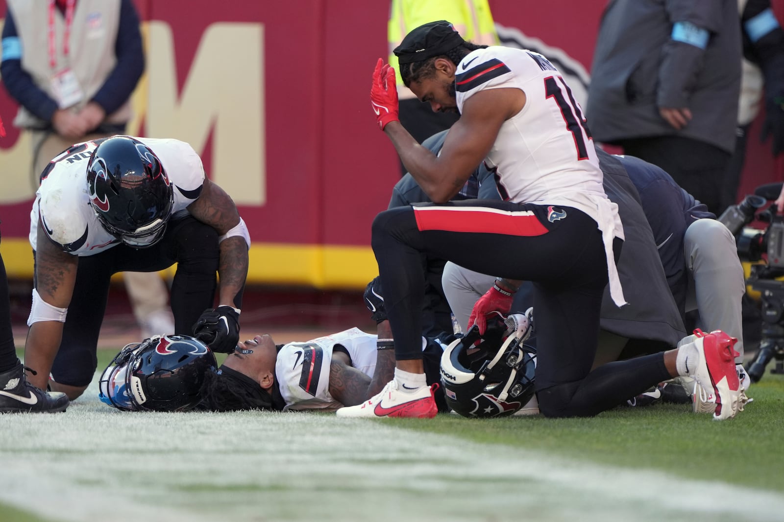 Houston Texans wide receiver Tank Dell is checked on by teammate Jared Wayne, right, after catching a touchdown pass and being injured during the second half of an NFL football game against the Kansas City Chiefs Saturday, Dec. 21, 2024, in Kansas City, Mo. (AP Photo/Charlie Riedel)