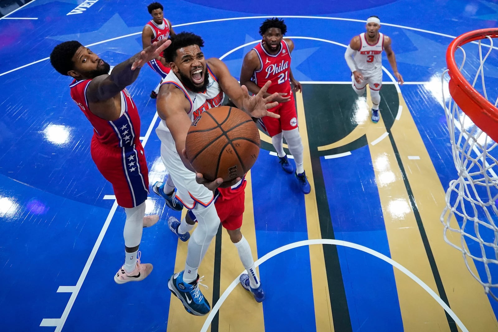 New York Knicks' Karl-Anthony Towns, center, goes up for a shot past Philadelphia 76ers' Paul George, left, during the second half of an Emirates NBA Cup basketball game, Tuesday, Nov. 12, 2024, in Philadelphia. (AP Photo/Matt Slocum)