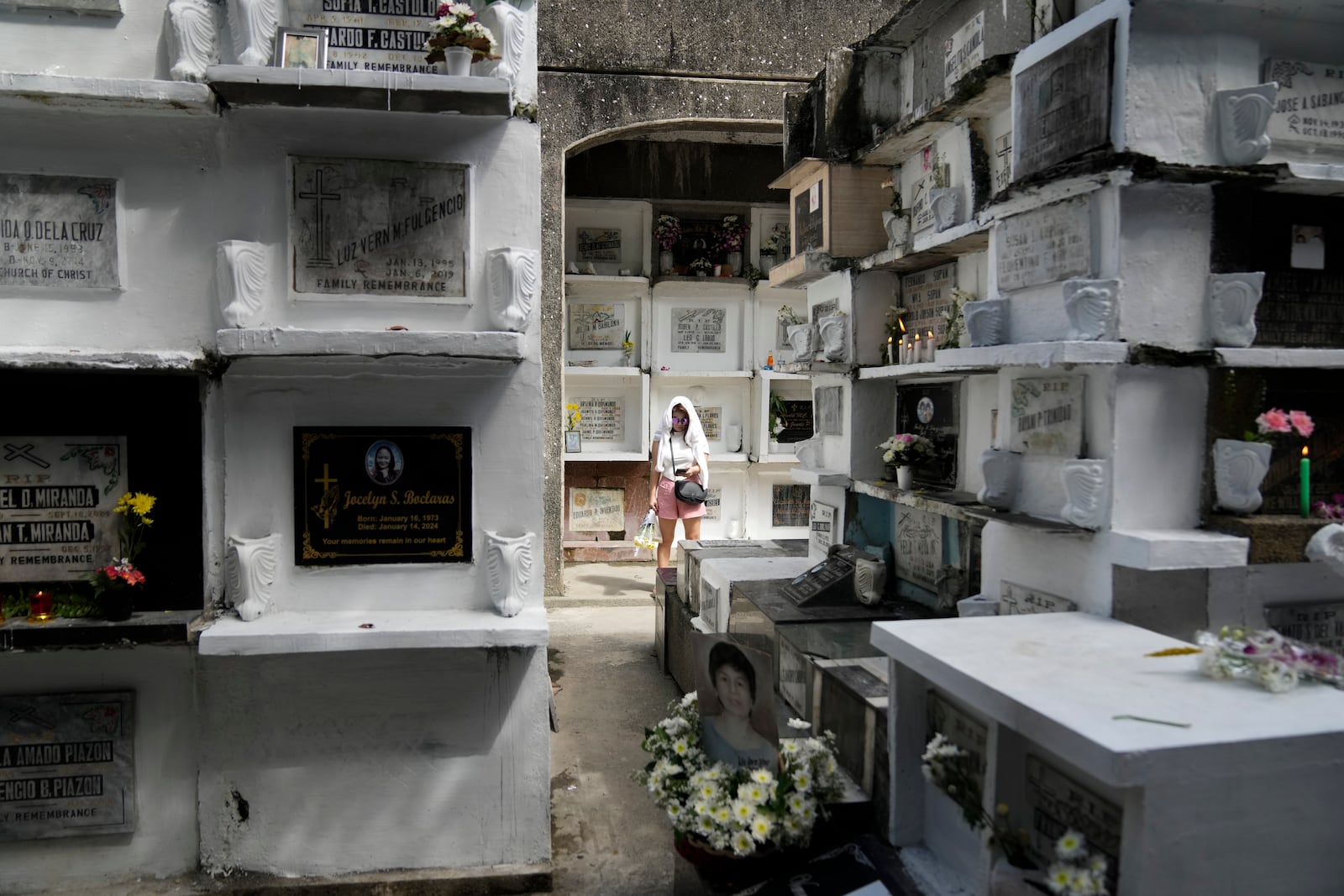 A woman stands in between apartment-type tombs at Manila's North Cemetery, Philippines as the nation observes All Saints Day on Friday, Nov. 1, 2024. (AP Photo/Aaron Favila)