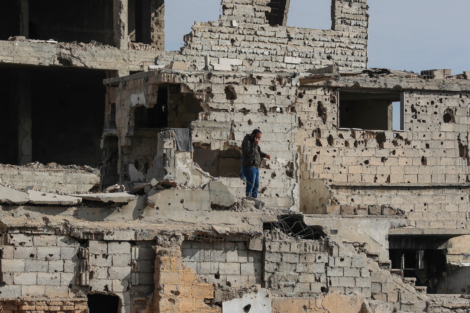 A Syrian man speaks on his mobile phone as stands on the stairs of a damaged building in the town of Harasta, east of Damascus, Syria, Thursday, Dec. 12, 2024. (AP Photo/Omar Sanadiki)