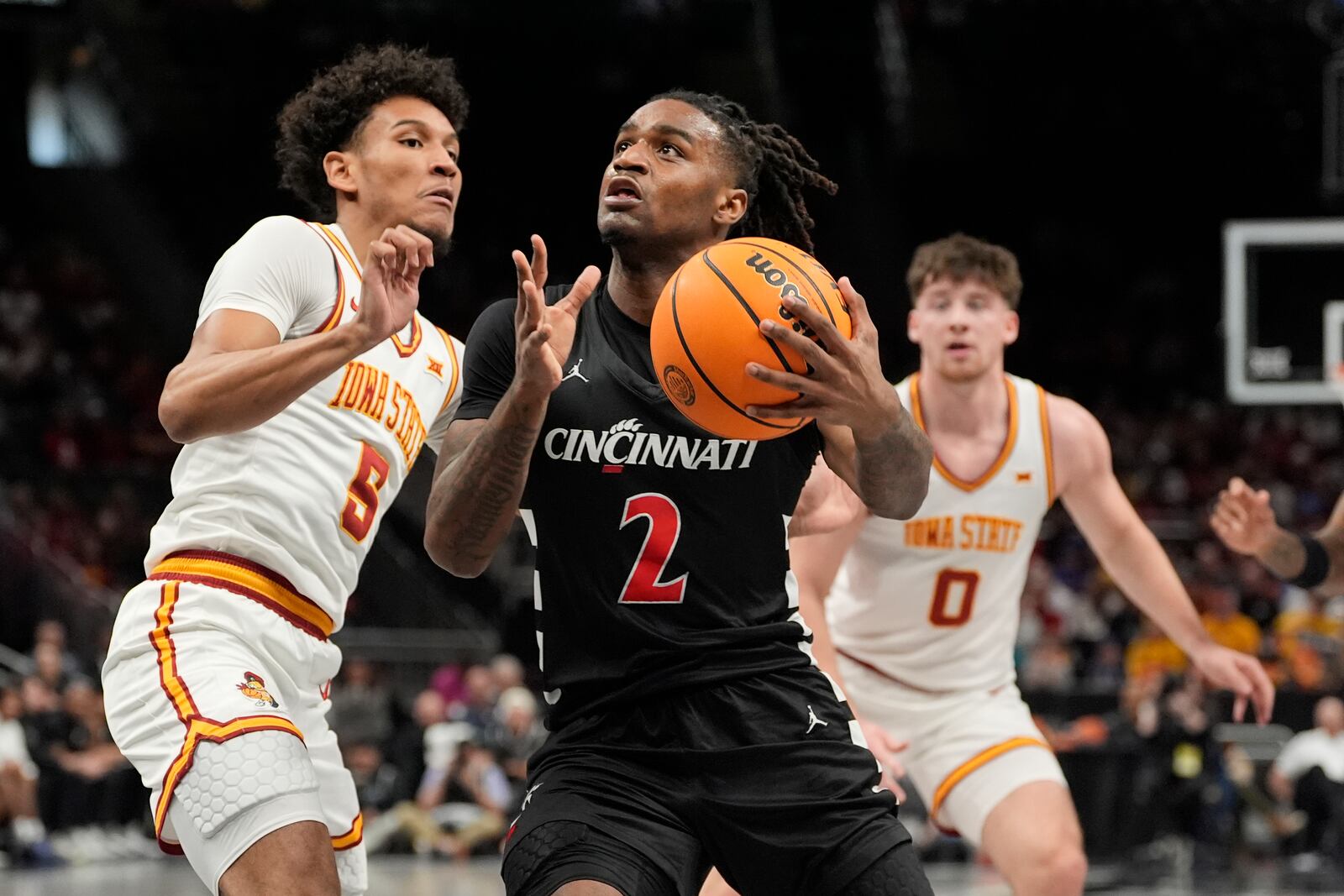 Cincinnati's Jizzle James (2) heads to the basket as Iowa State's Curtis Jones (5) and Nate Heise (0) defend during the first half of an NCAA college basketball game in the second round of the Big 12 Conference tournament, Wednesday, March 12, 2025, in Kansas City, Mo. (AP Photo/Charlie Riedel)