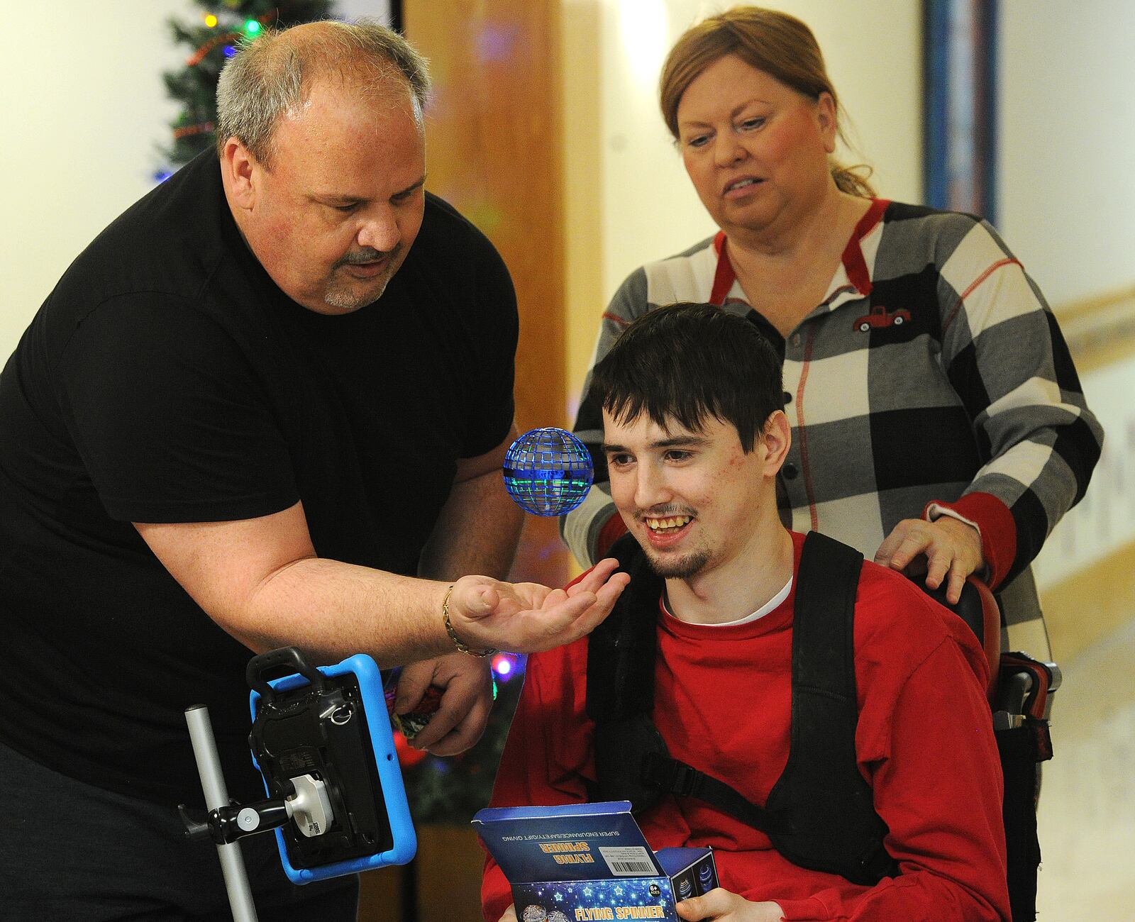 Stephen L. smiles at his gift he received in the Holiday Giving Tree gift drive at Stillwater Center on Tuesday, Dec. 19, 2023. Stillwater Center staff members Justin Allen and Shanda Sulfridge helped him open the flying spinner. MARSHALL GORBY\STAFF