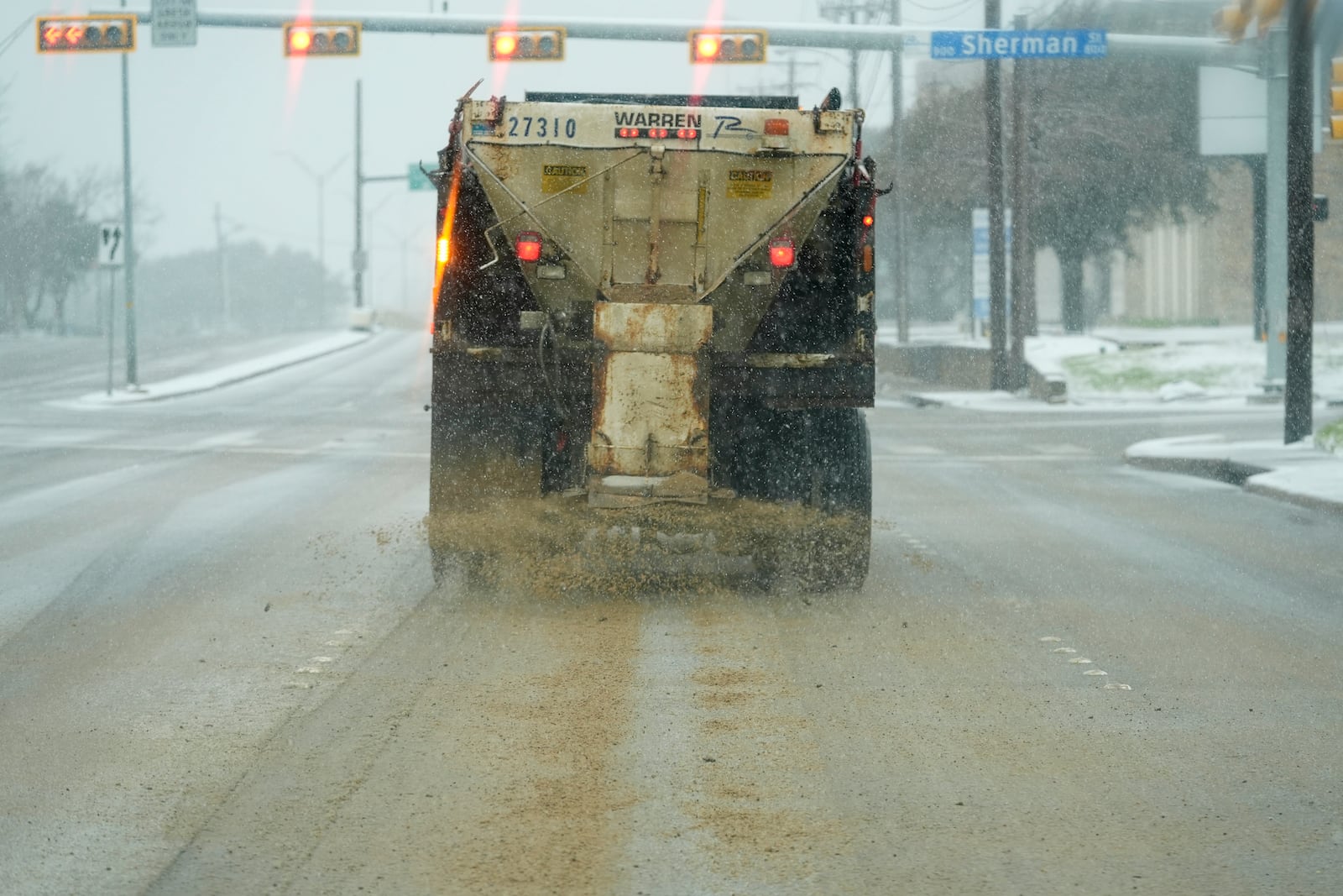 A truck treats a road for better driving conditions as snow falls Thursday, Jan. 9, 2025, in Dallas. (AP Photo/LM Otero)