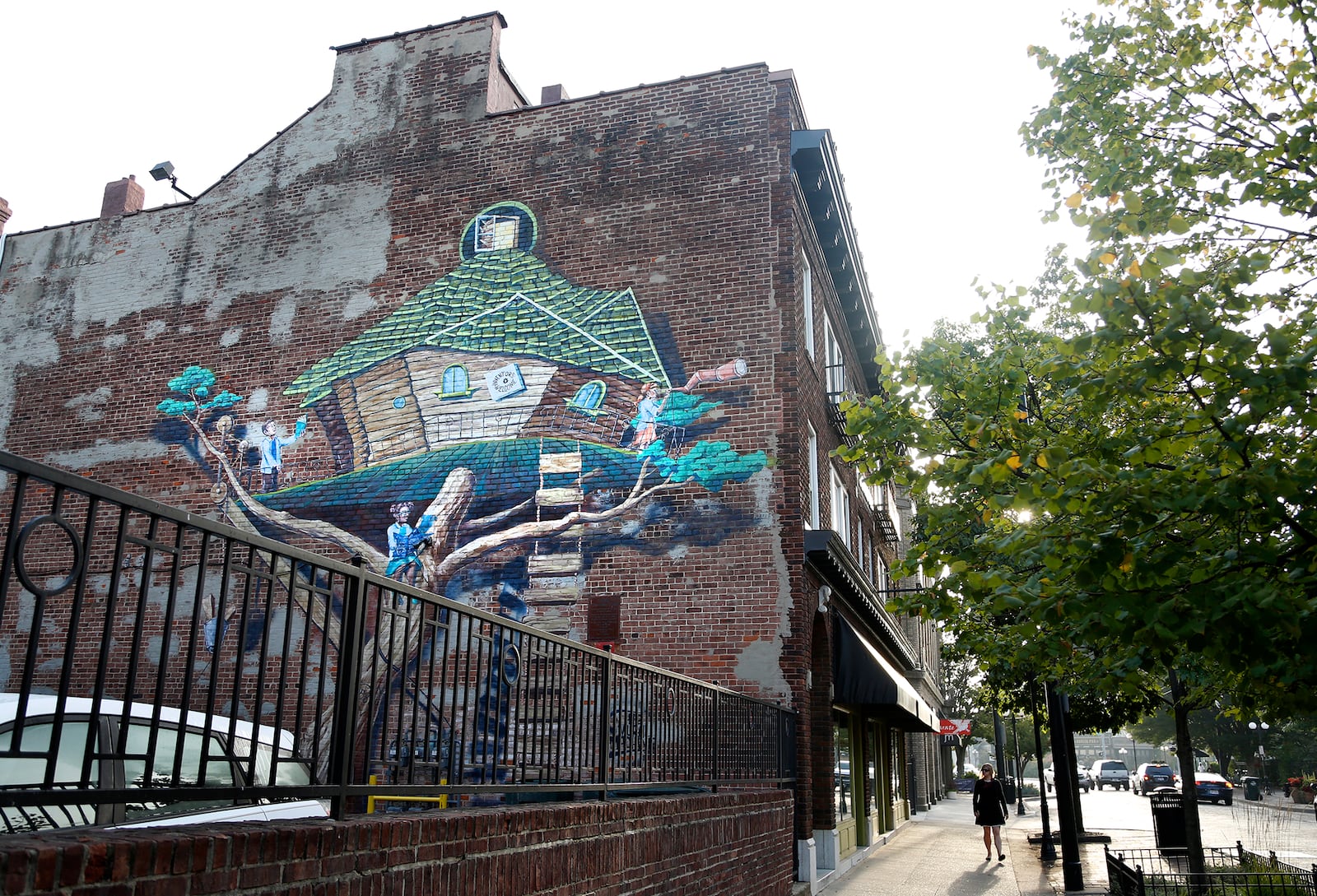 The whimsical Inventors Tree house, created by the Mural Machine, climbs up the side of a brick building that houses the Clash boutique and gallery, 521 E. Fifth St. LISA POWELL / STAFF