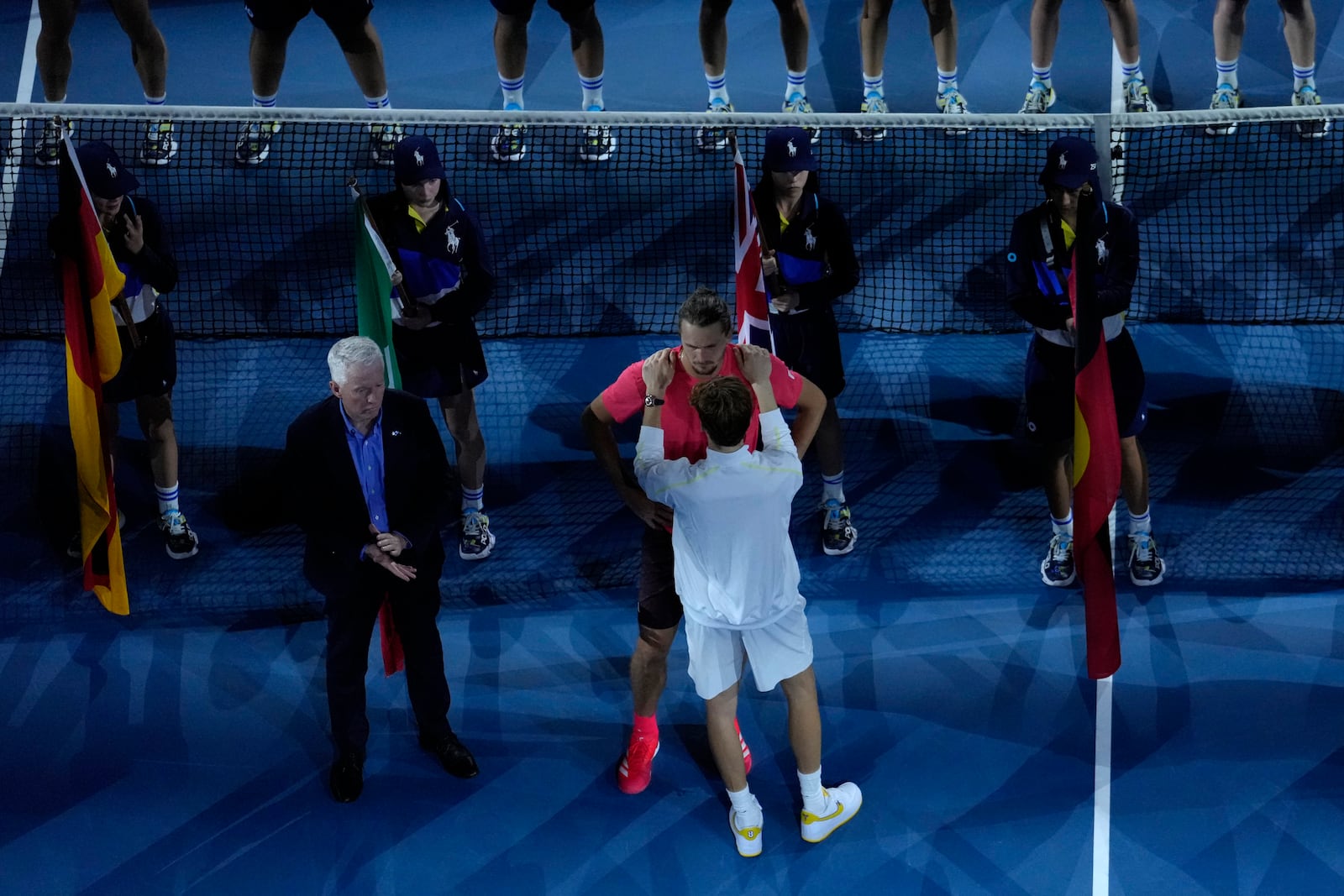 Jannik Sinner of Italy, in white, comforts Alexander Zverev of Germany after defeating him in the men's singles final at the Australian Open tennis championship in Melbourne, Australia, Sunday, Jan. 26, 2025. (AP Photo/Manish Swarup)