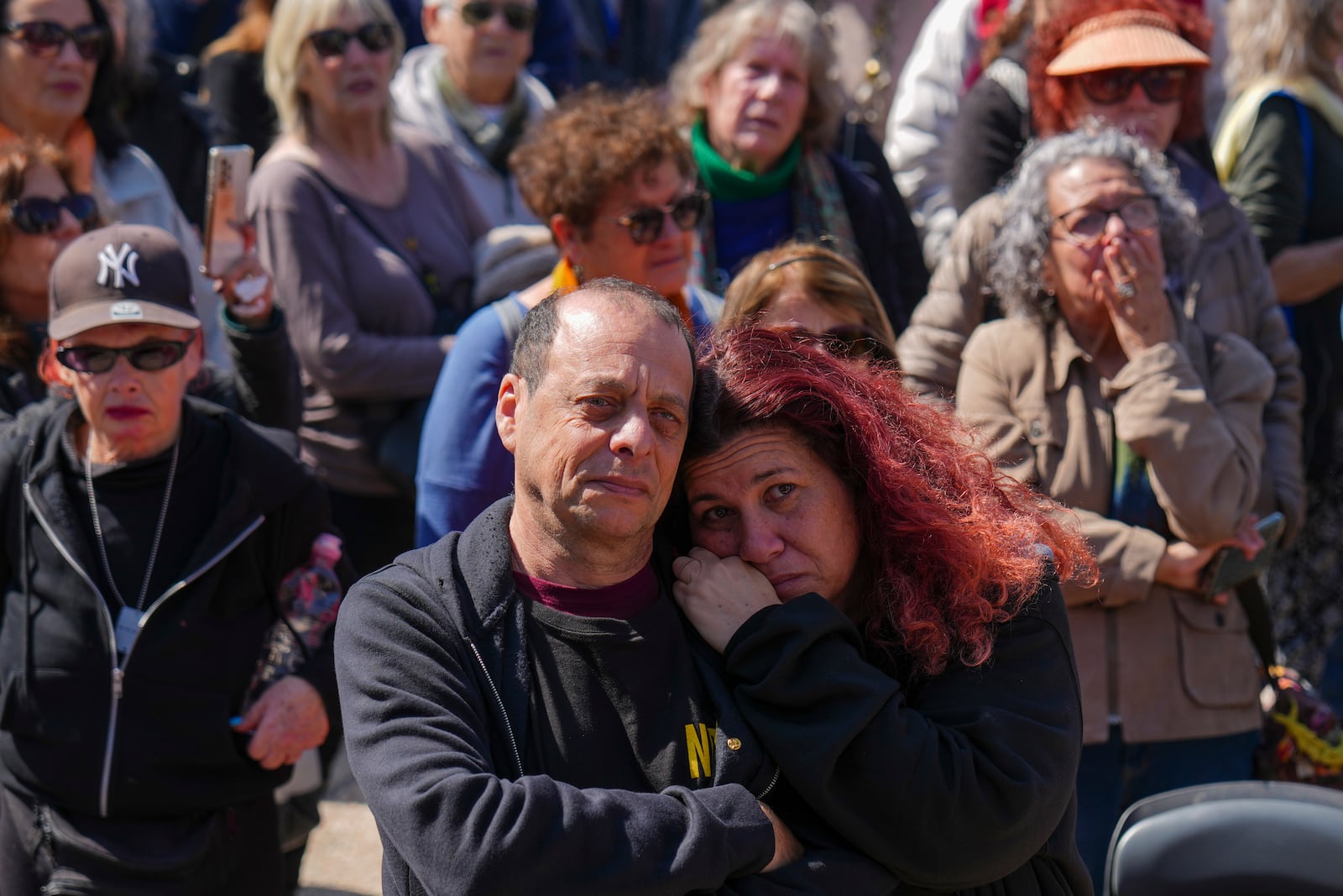 People watch a live broadcast from the funeral of slain hostages Shiri Bibas and her two children, Ariel and Kfir, at a plaza known as the Hostages Square in Tel Aviv, Israel, Wednesday, Feb. 26, 2025. The mother and her two children were abducted by Hamas on Oct. 7, 2023, and their remains were returned from Gaza to Israel last week as part of a ceasefire agreement with Hamas. (AP Photo/Ariel Schalit)