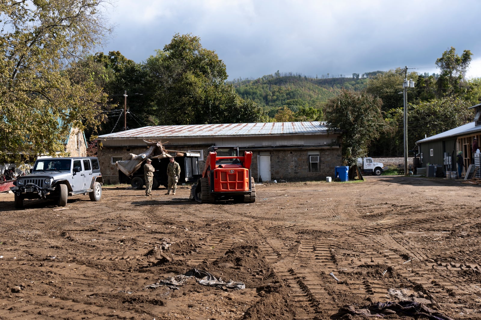 National Guard members talk behind the Hot Springs Community Center, the ground muddied by flooding, during restoration efforts in the aftermath of Hurricane Helene, on Oct. 16, 2024, in Hot Springs, N.C. (AP Photo/Stephanie Scarbrough)