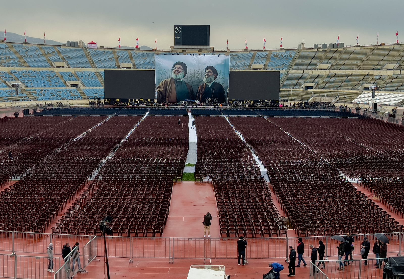 Photographers take pictures of workers setting up the chairs at Beirut's City Sportive stadium during preparation a day ahead of the funeral procession of Hezbollah leaders Sayyed Hassan Nasrallah and Sayyed Hashem Safieddine, in Beirut, Lebanon, Saturday, Feb. 22, 2025. (AP Photo/Hussein Malla)