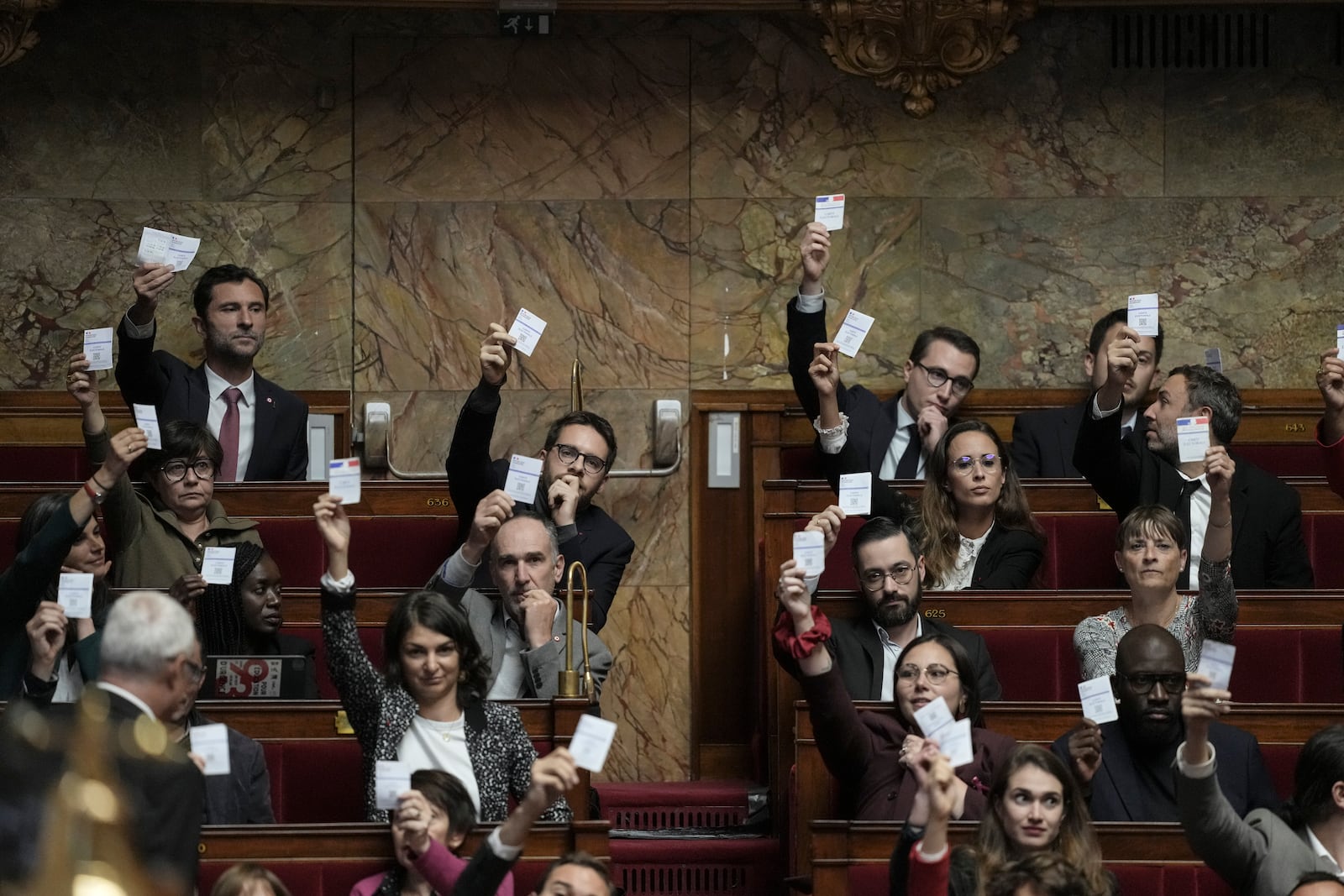 Members of the French unbowed party show their voting cards during the speech Prime Minister Michel Barnier arrives at the National Assembly, in Paris, Tuesday, Oct. 1, 2024. (AP Photo/Thibault Camus)