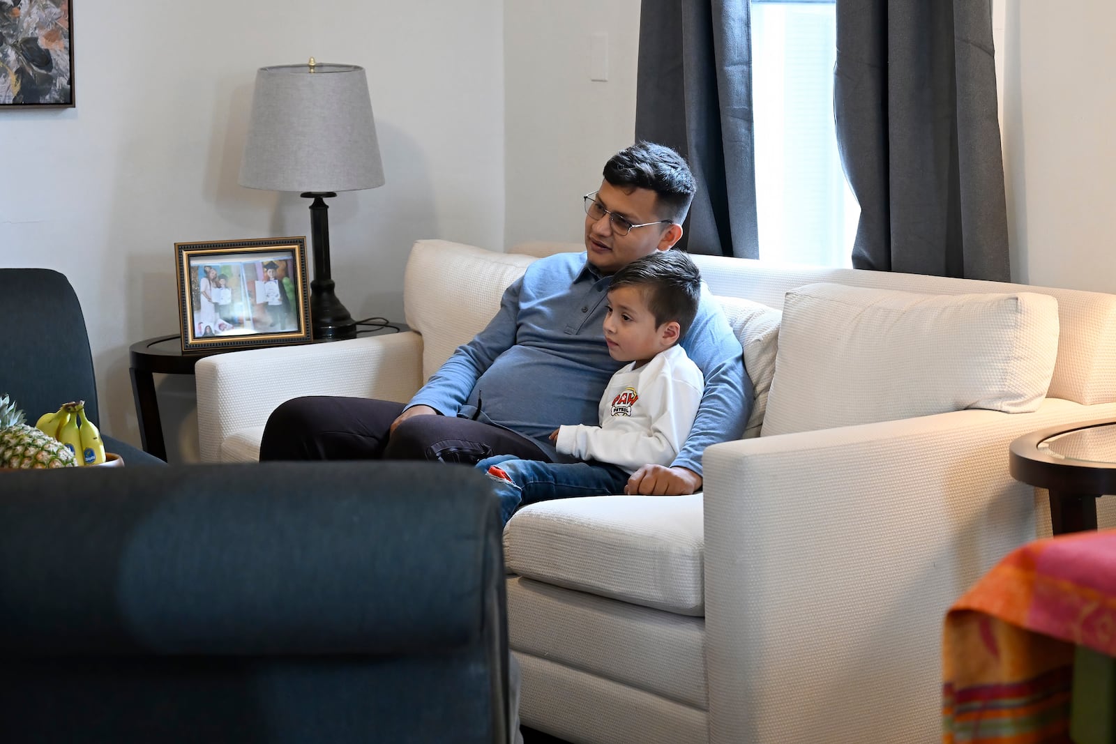 In this Jan. 3, 2025 photo, Rogers Lopez watches television with his son Jesus Lopez in their apartment in New Milford, Conn. (AP Photo/Jessica Hill)