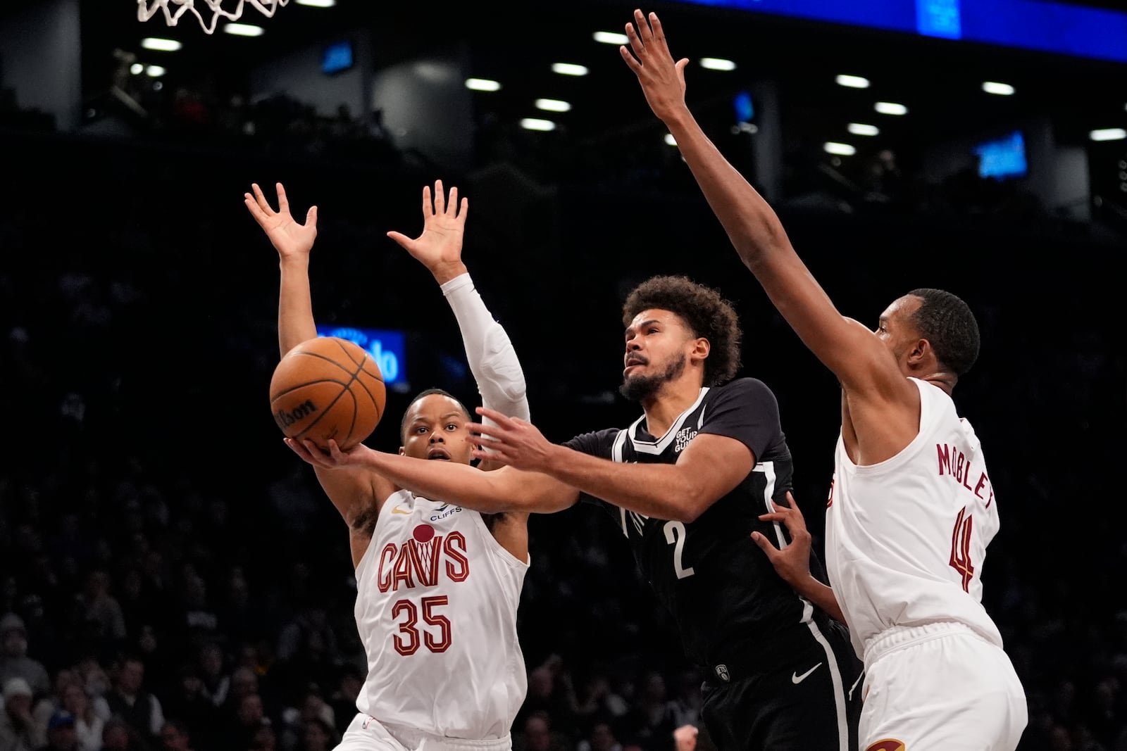 Brooklyn Nets' Cameron Johnson (2) drives past Cleveland Cavaliers' Isaac Okoro (35) and Evan Mobley (4) during the second half of an NBA basketball game Thursday, Feb. 20, 2025, in New York. (AP Photo/Frank Franklin II)