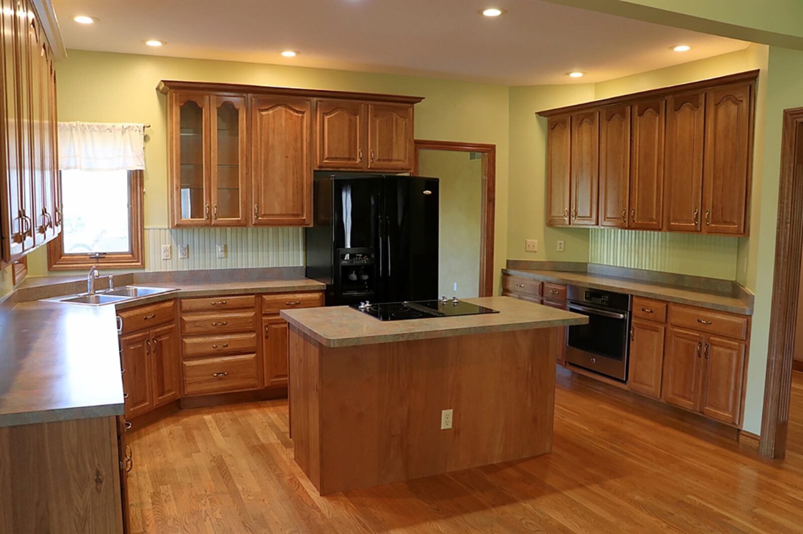 Kitchen cabinets wrap around four walls and the stainless-steel appliances. The cabinetry and complementing countertops provide space for just about everything, including a planning area, a buffet counter with oven, and an island with glass cooktop. CONTRIBUTED PHOTO BY KATHY TYLER