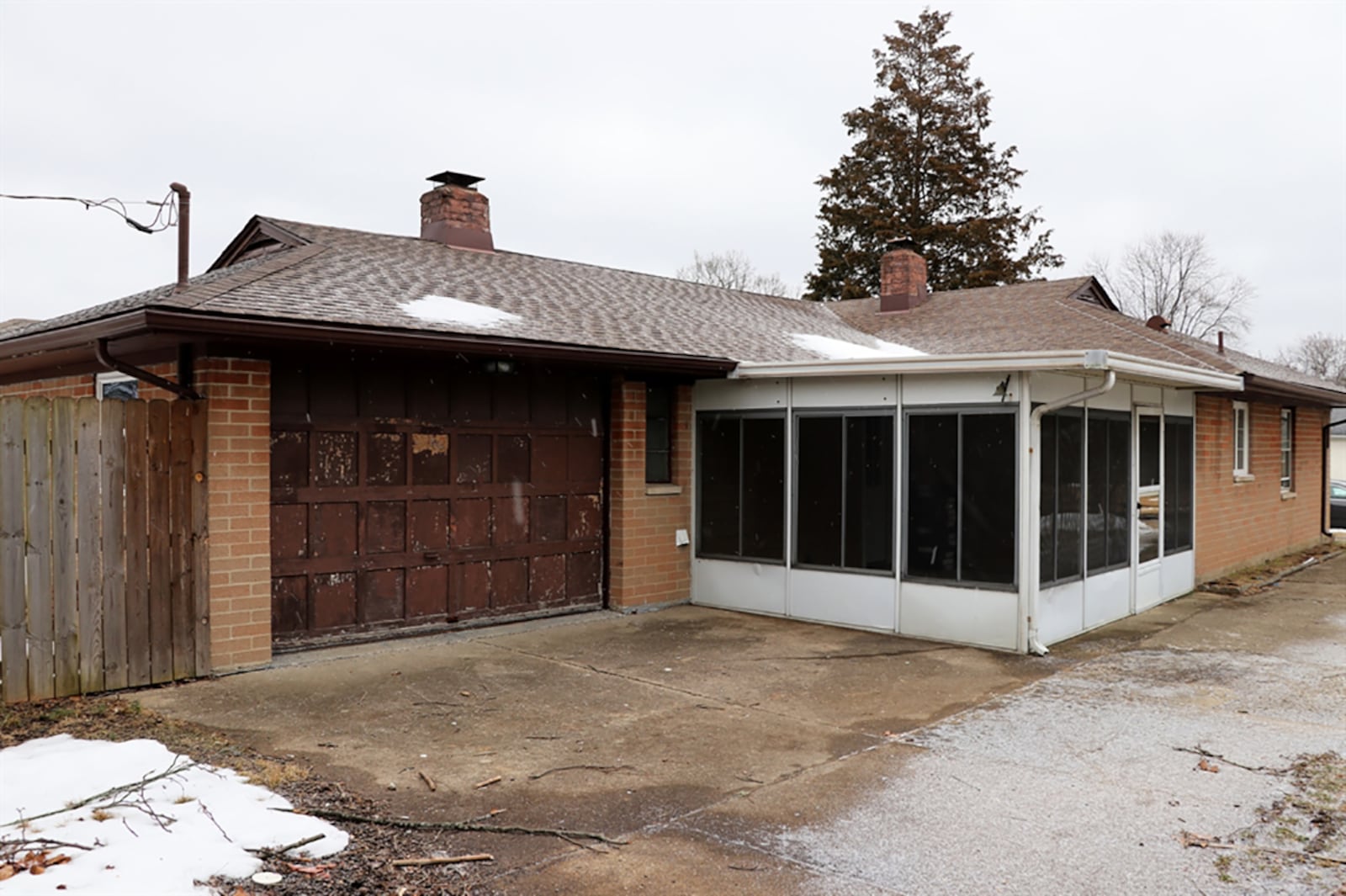 The enclosed porch has a concrete floor, wood-plank walls and screen-enclosed windows. A concrete driveway leads up to the side of the house and wraps around to the garage at the back of the house. A new garage door is on a delayed order. CONTRIBUTED PHOTO BY KATHY TYLER