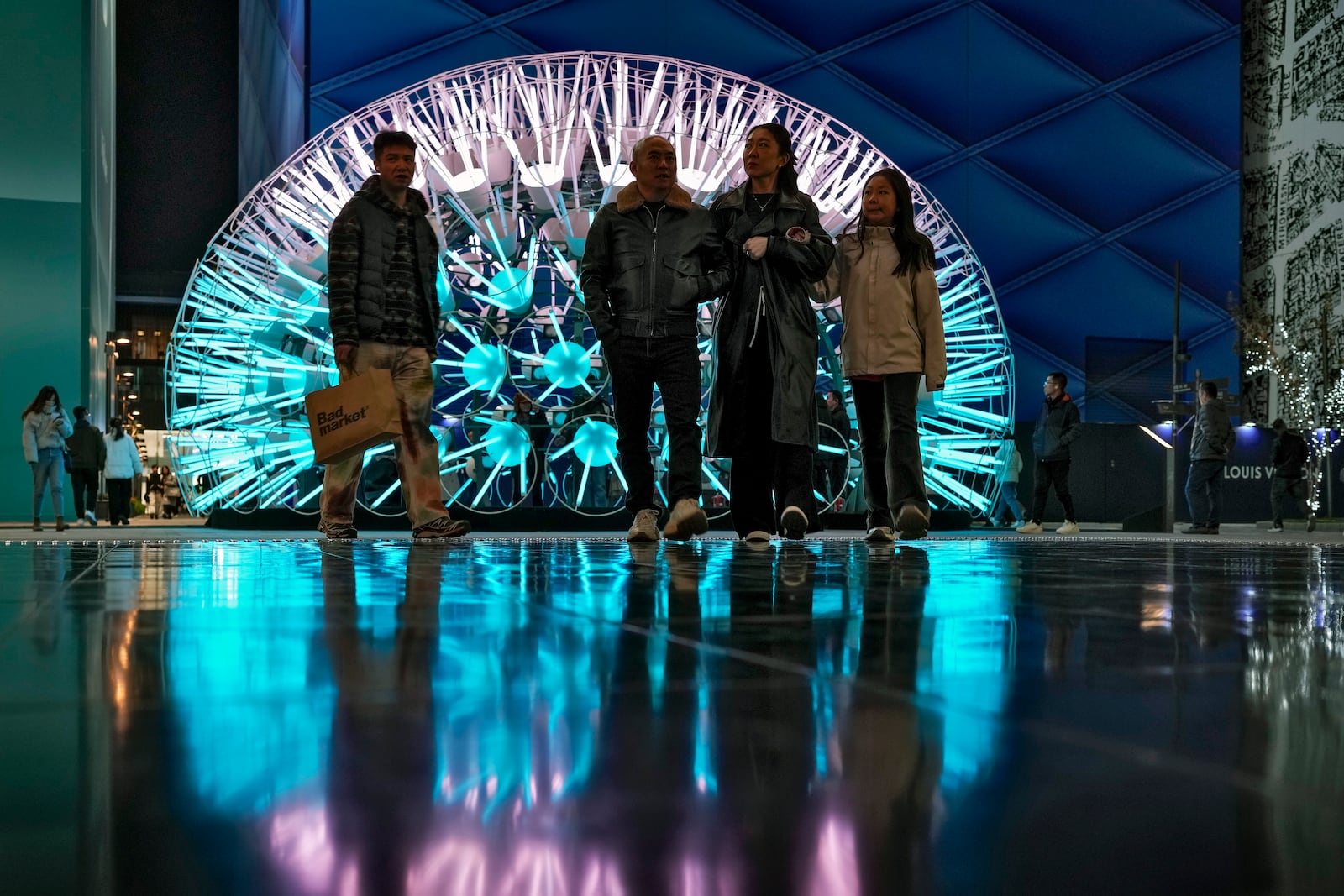 Shoppers walk around art light structures on display at a popular outdoor shopping mall in Beijing, on Nov. 17, 2024. (AP Photo/Andy Wong)