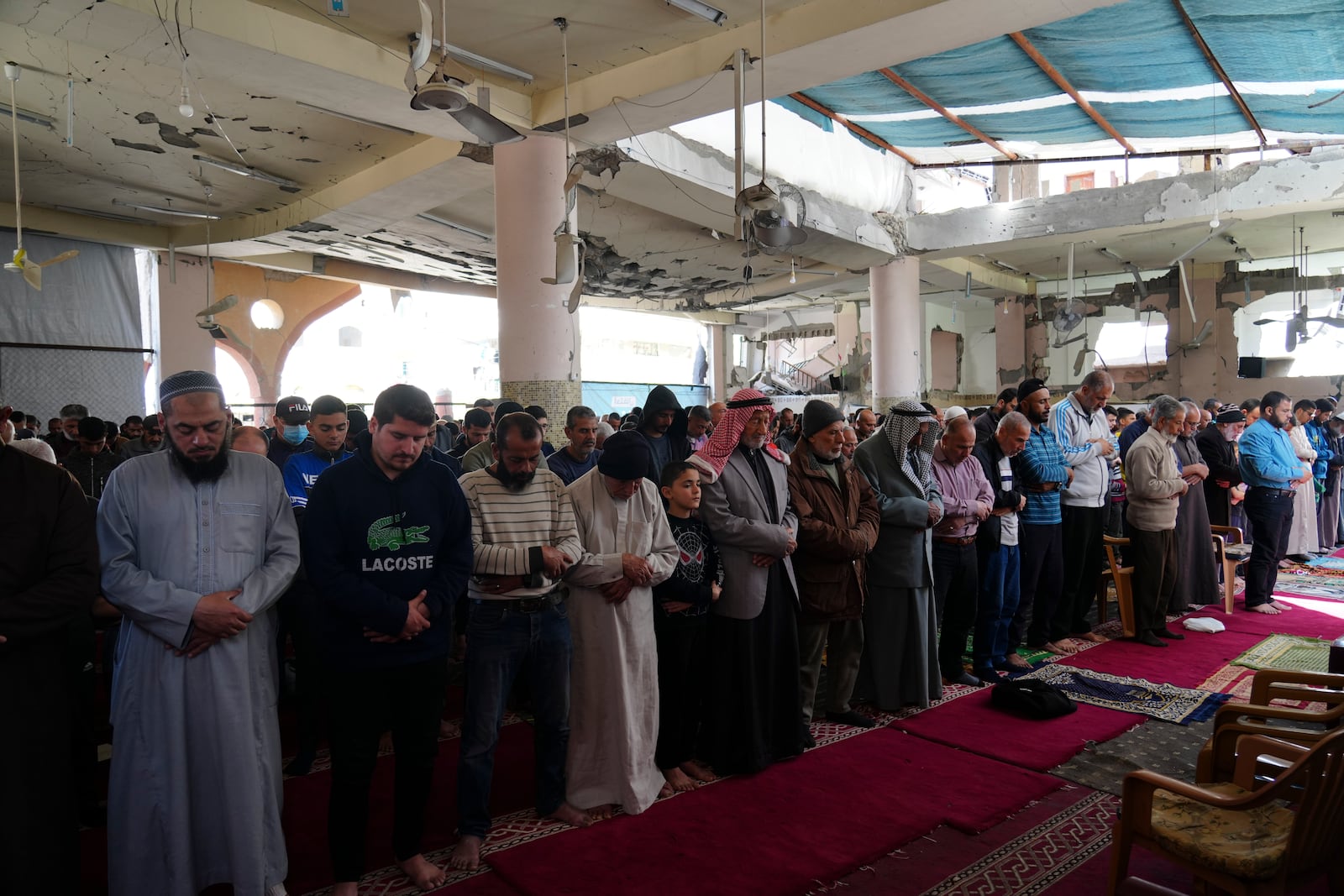 Palestinians take part in Friday prayers in the ruins of a Mosque that was partially destroyed by Israeli bombardment, in Nuseirat, Gaza Strip, Friday, March 14, 2025, during the holy Muslim month of Ramadan. (AP Photo/Abdel Kareem Hana)