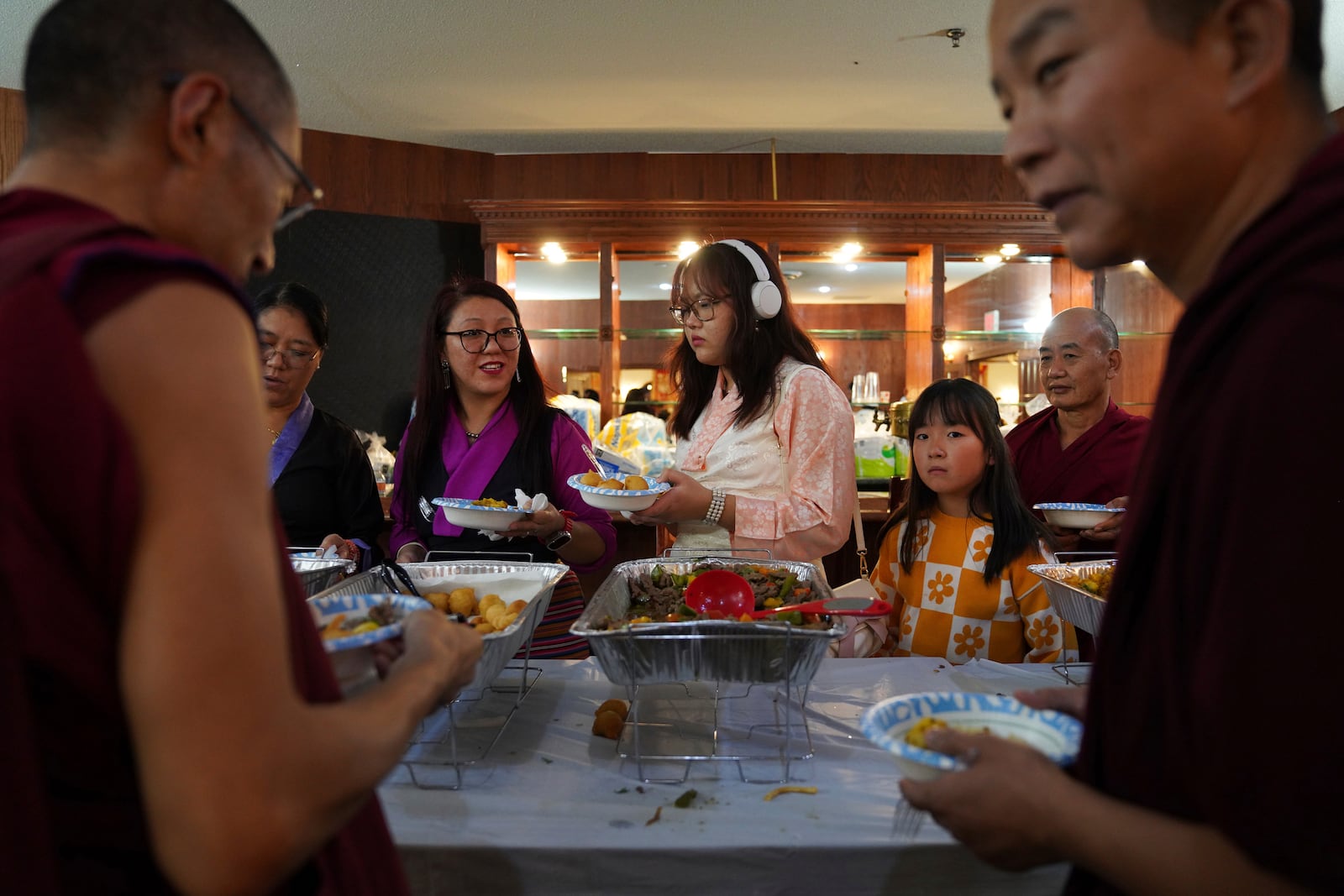 Guests and monks choose from a wide selection of homemade Tibetan dishes at the 18th birthday and enthronement ceremony for U.S.-born Buddhist lama, Jalue Dorje, in Isanti, Minn., on Saturday, Nov. 9, 2024. (AP Photo/Jessie Wardarski)