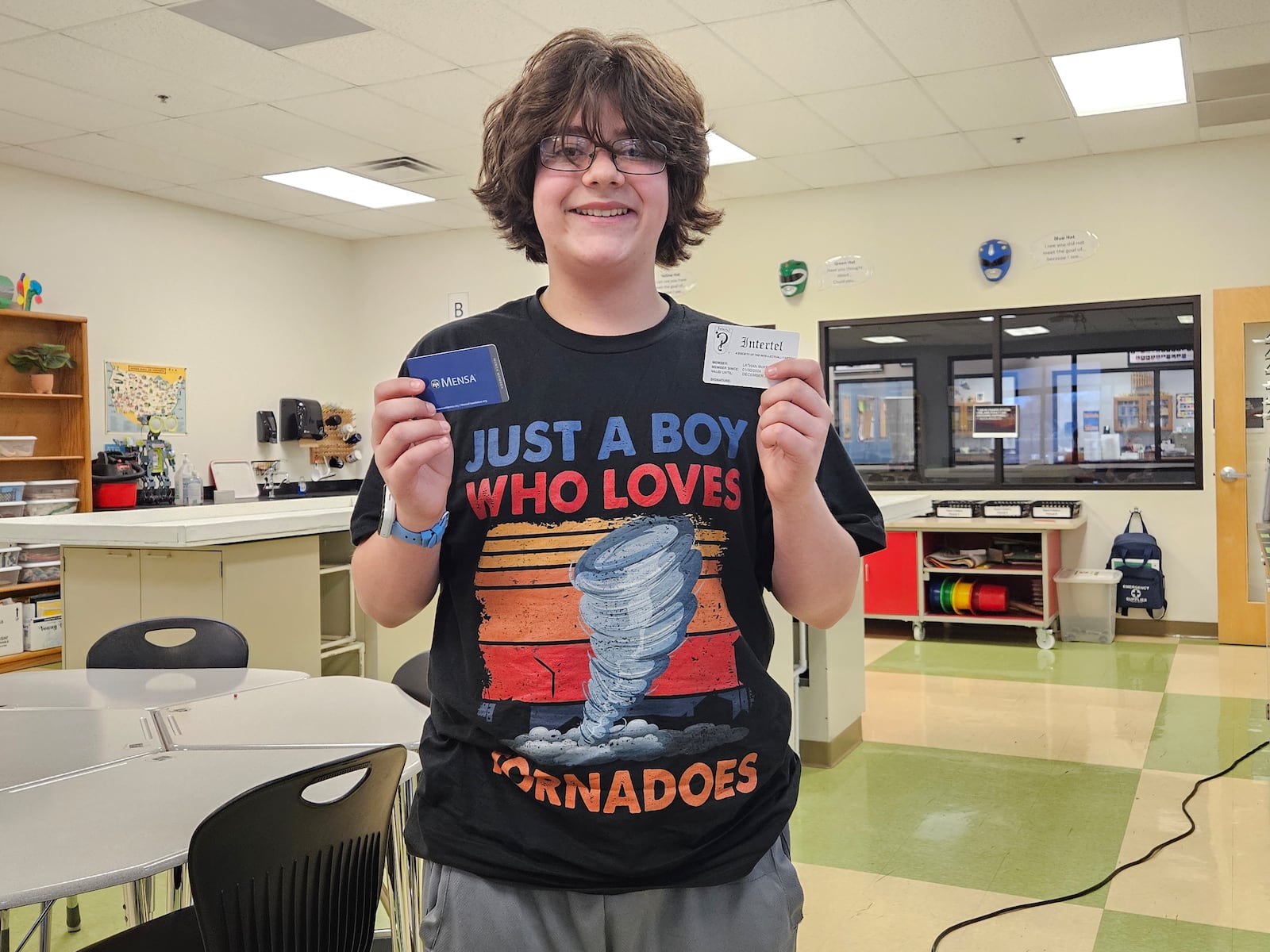 Lathan McKeel smiles while holding his Mensa and Intertel membership cards. JESSICA GRAUE/STAFF