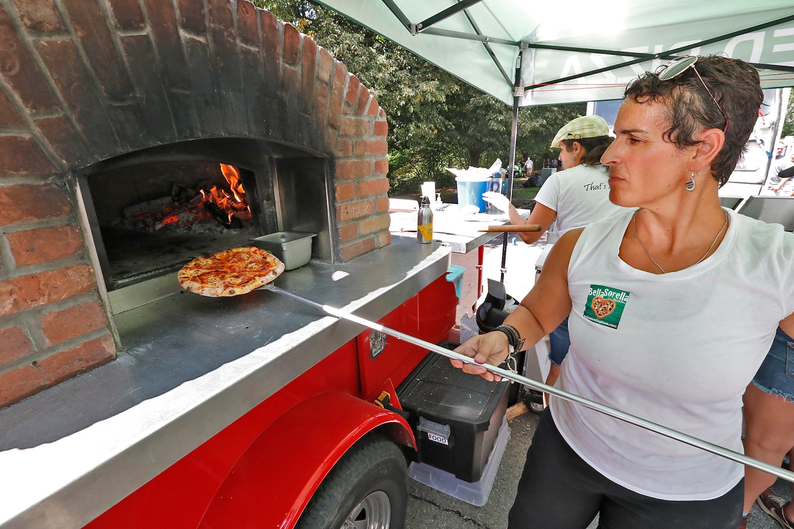 Elizabeth Weizman takes a pizza out of a portable wood fired brick oven at the Bella Sorella Pizza food truck during the 2017 Springfield Rotary Food Truck Competition in Veteran's Park. BILL LACKEY/STAFF