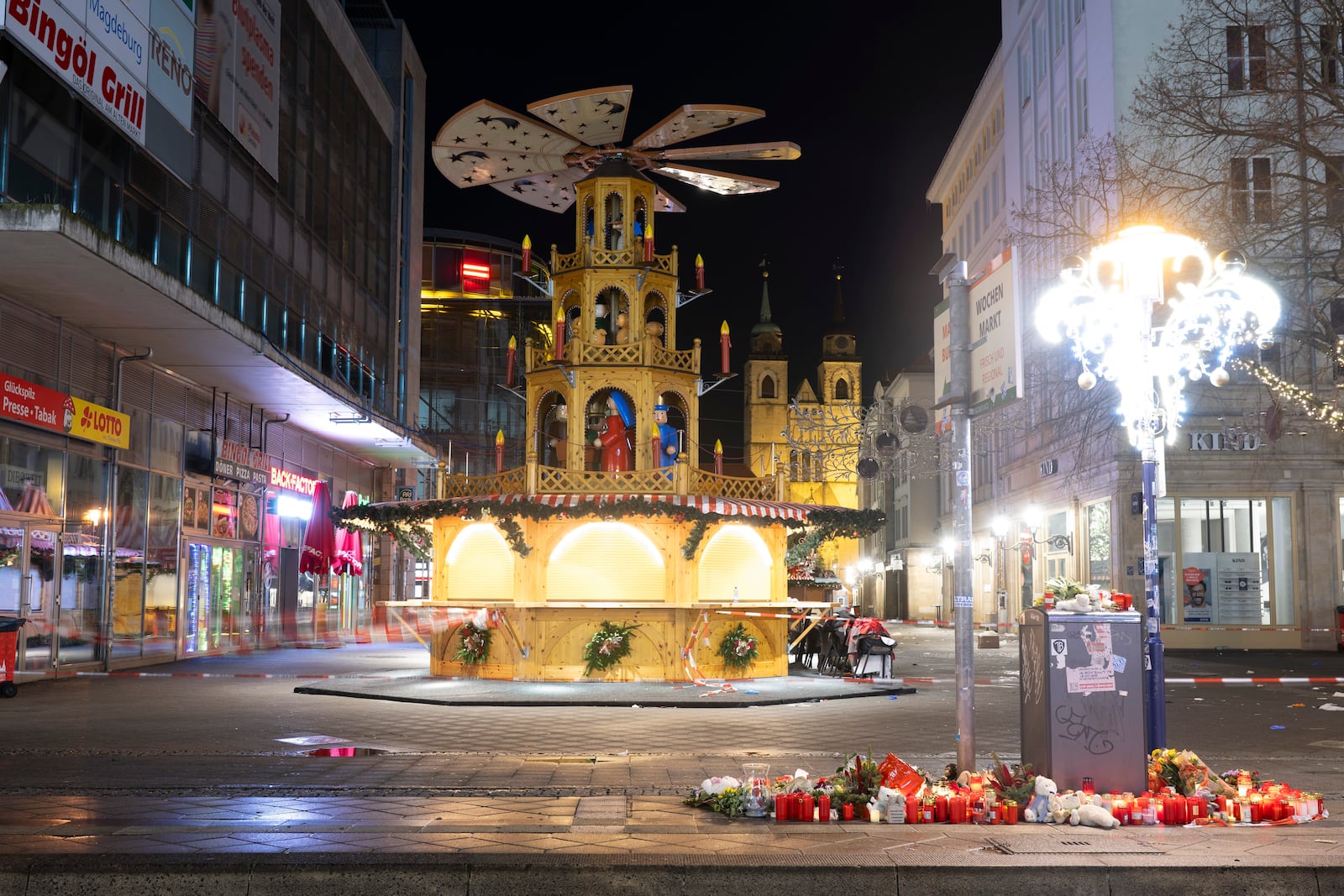 Candles and flowers sit in front of the Christmas market early Sunday, Dec. 22, 2024, in Magdeburg, Germany, after a car drove into a crowd at the market on Friday, Dec. 20. (Sebastian Kahnert/dpa via AP)