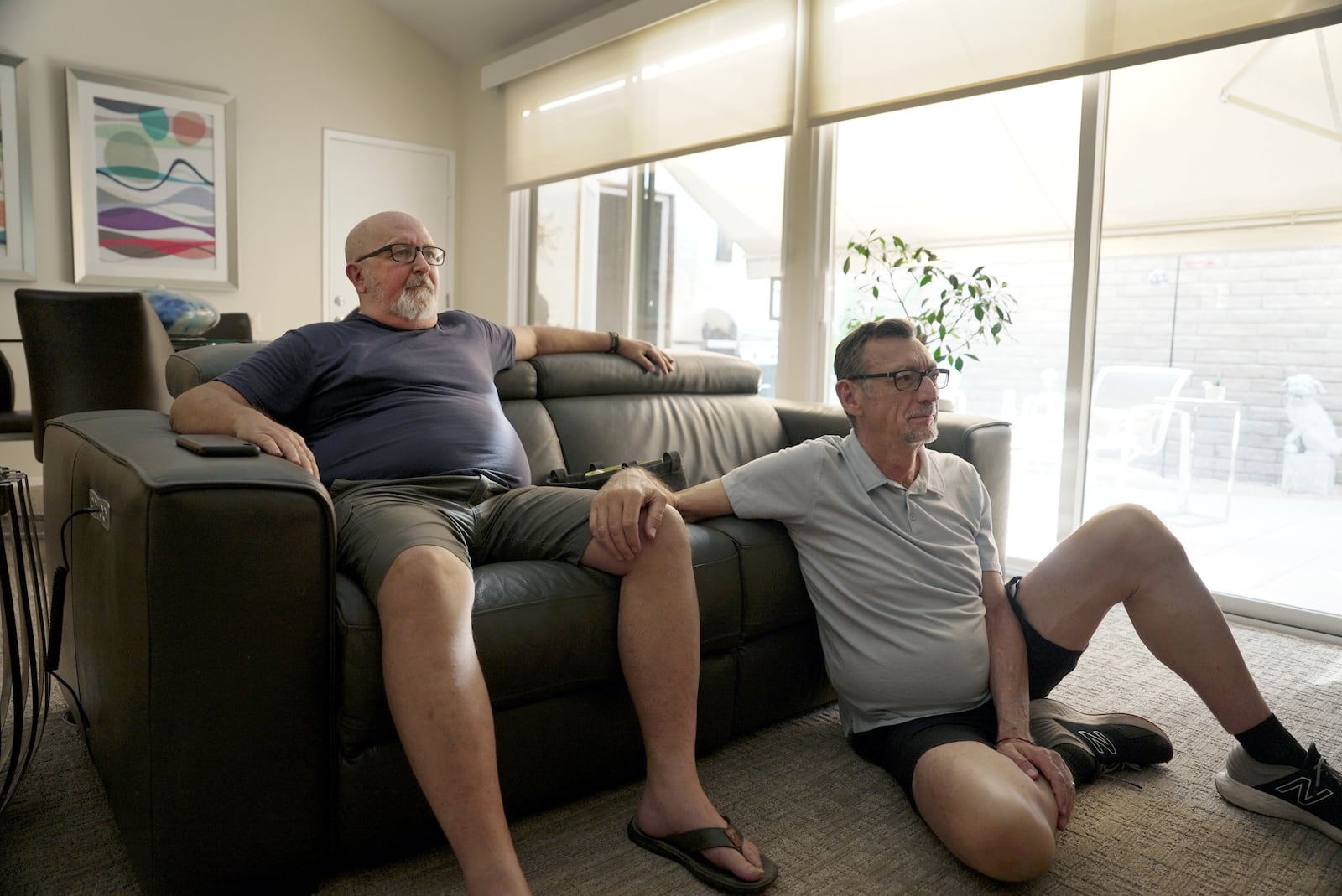 Carl McNew watches television with his husband Steve Hunter in Palm Springs, Calif., on Sept. 12, 2024. (AP Photo/Shelby Lum)