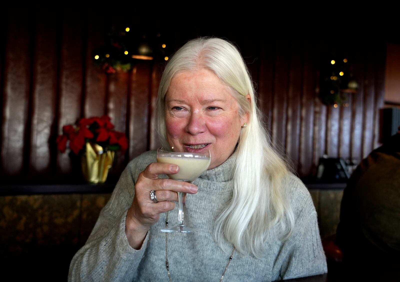 Laurie Kenny takes a sip of eggnog at Scoma's Restaurant in San Francisco on Dec. 10, 2024. The eggnog is prepared 11 months in advance. (AP Photo/Terry Chea)