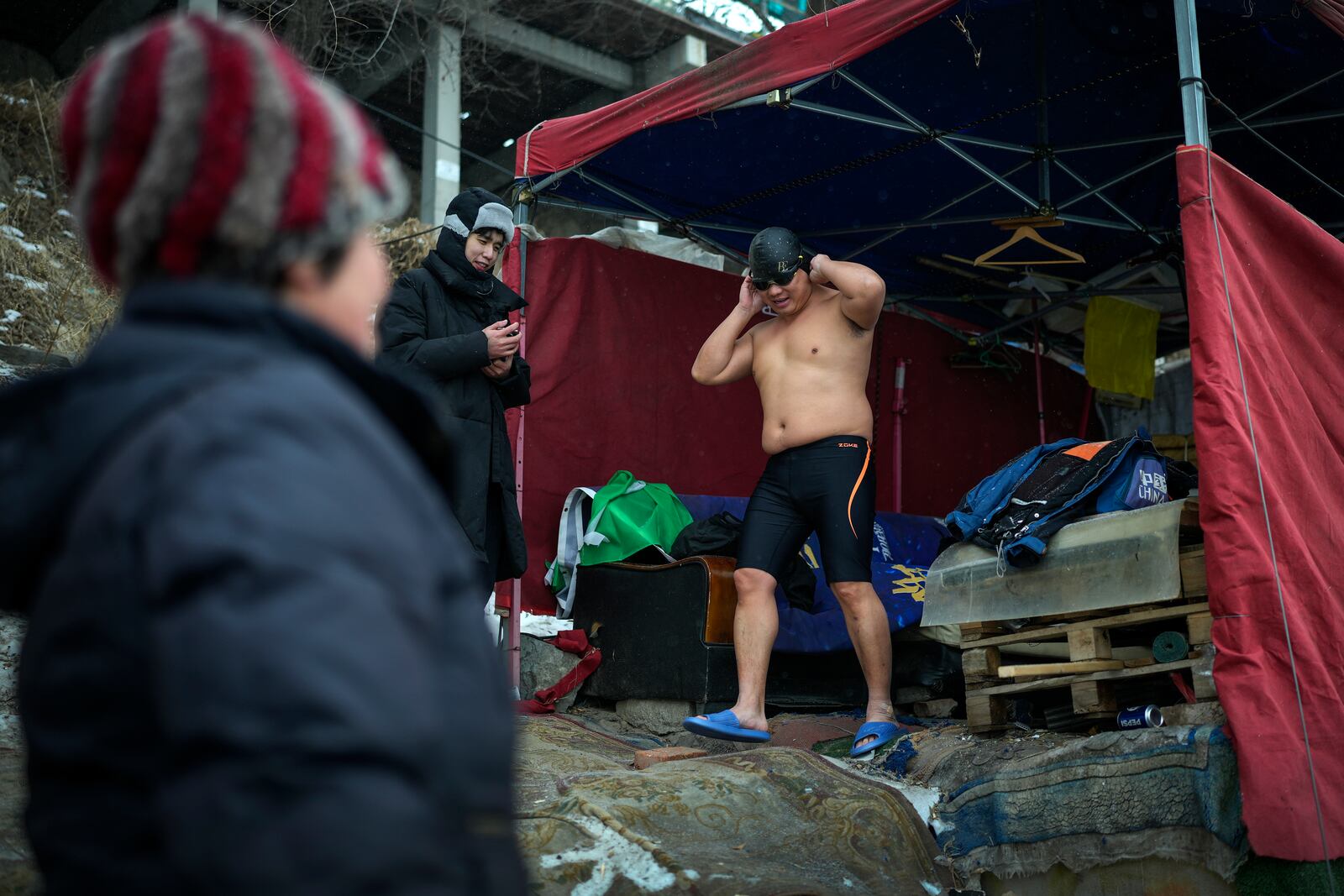 Residents watch a man preparing to swim in the frozen Songhua river in Harbin in northeastern China's Heilongjiang province, Tuesday, Jan. 7, 2025. (AP Photo/Andy Wong)