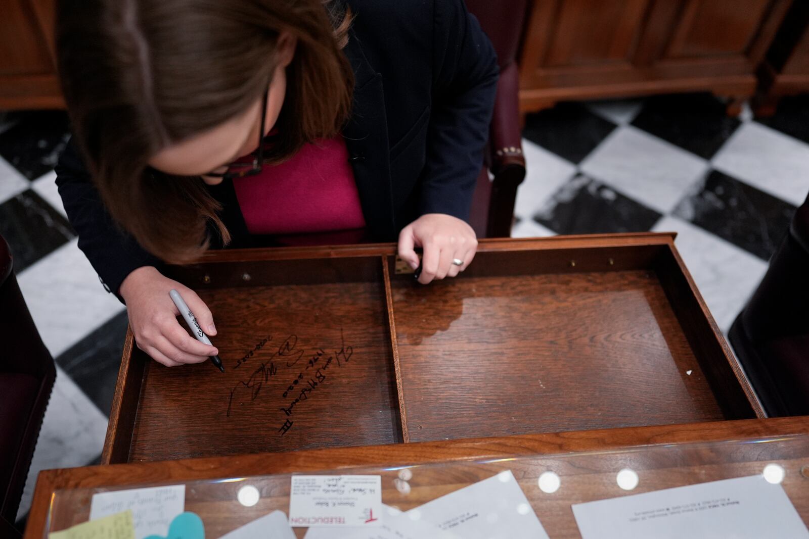 U.S.-Rep.-elect Sarah McBride, D-Del., signs her desk drawer on the Senate floor on her last day as a Delaware state senator at the Delaware Legislative Hall in Dover, Del., Monday, Dec. 16, 2024. (AP Photo/Carolyn Kaster)