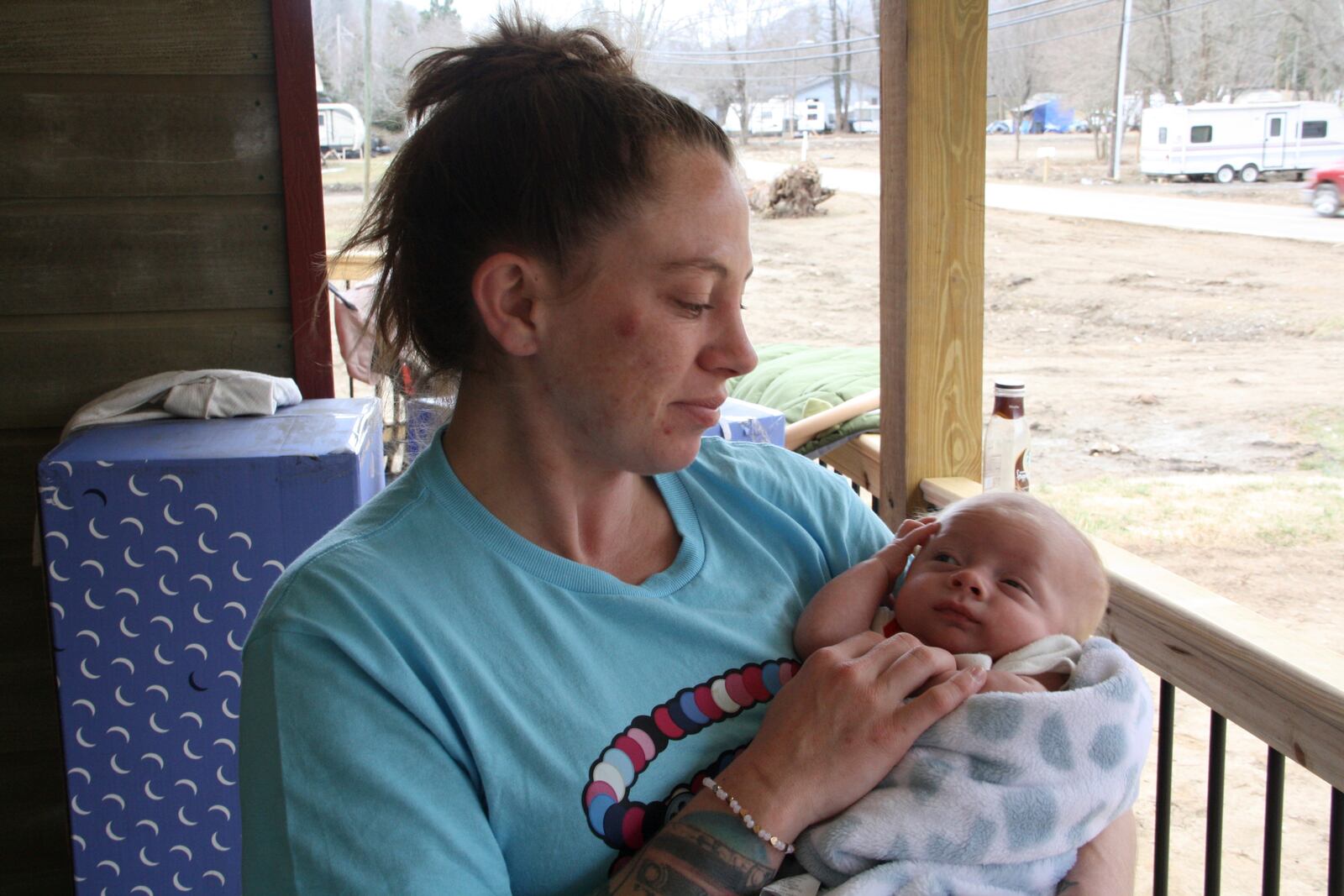 Emily Russell holds her infant son on her front porch, which was built by volunteers, in Swannanoa, N.C., on Thursday, Feb. 6, 2025. (AP Photo/Makiya Seminera)