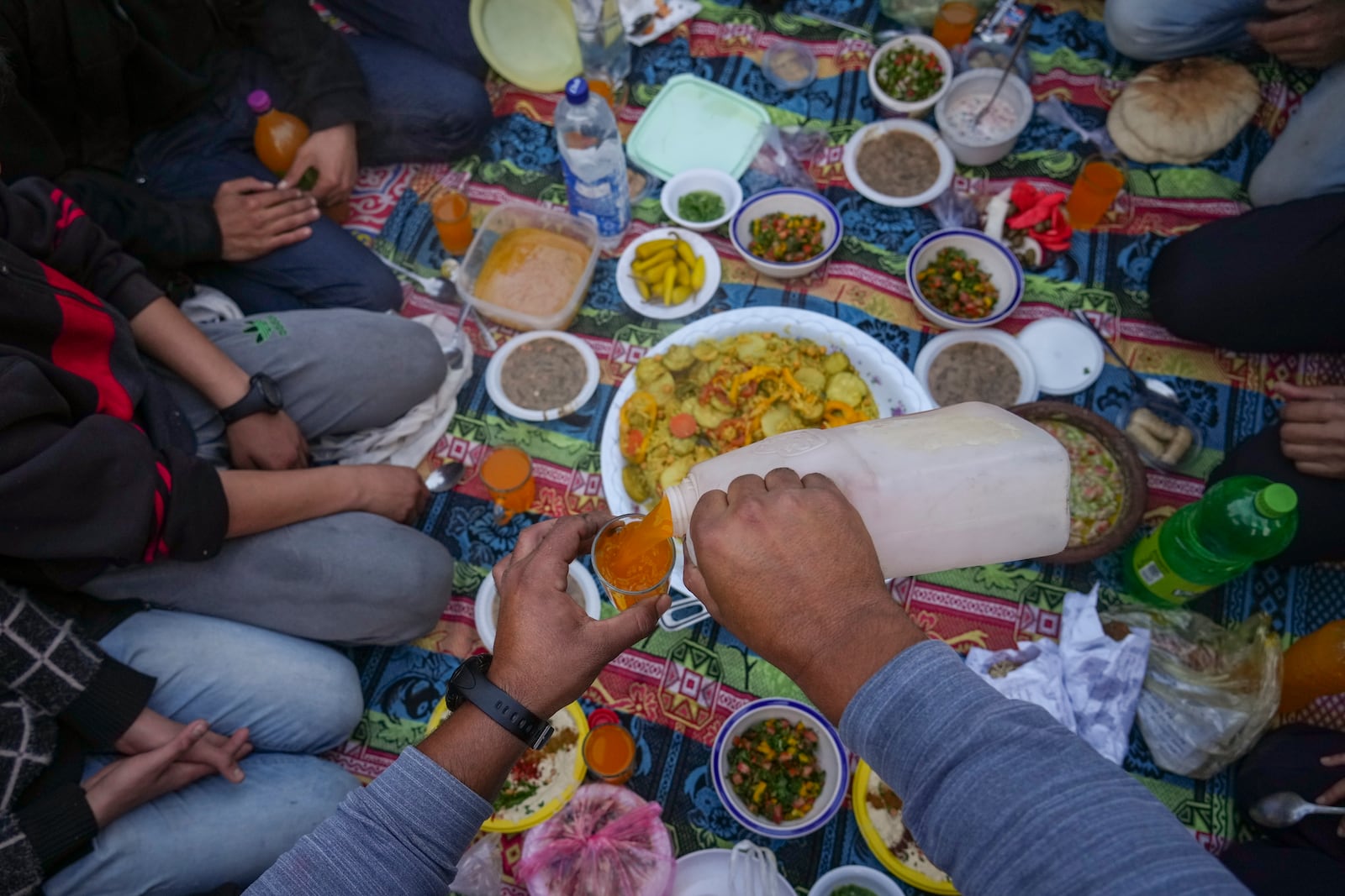 A man serves a juice as Palestinians prepare for Iftar, the fast-breaking meal during Ramadan in a street of the war-devastated Beit Lahia, northern Gaza Strip, Saturday, March 15, 2025. (AP Photo/Jehad Alshrafi)