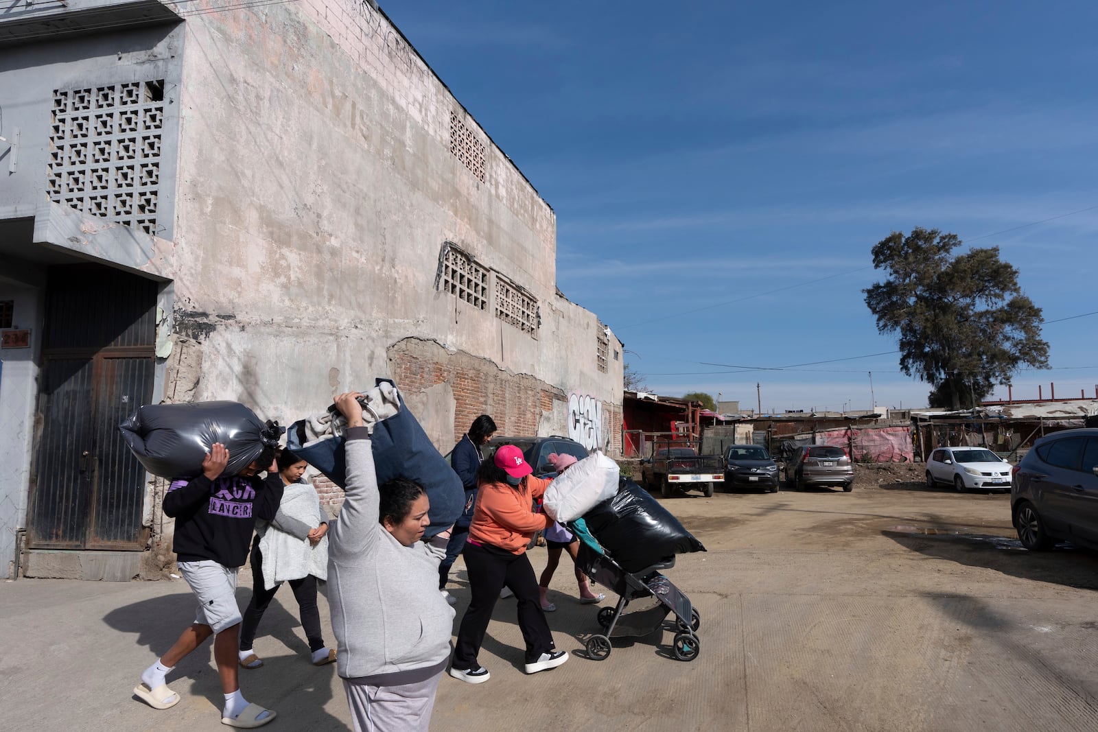 Margelis Rodriguez, of Venezuela, center, pushes a stroller packed with laundry as her family and others from a migrant shelter make their way to a nearby laundromat in Tijuana, Mexico, Friday, Jan. 31, 2025. (AP Photo/Gregory Bull)