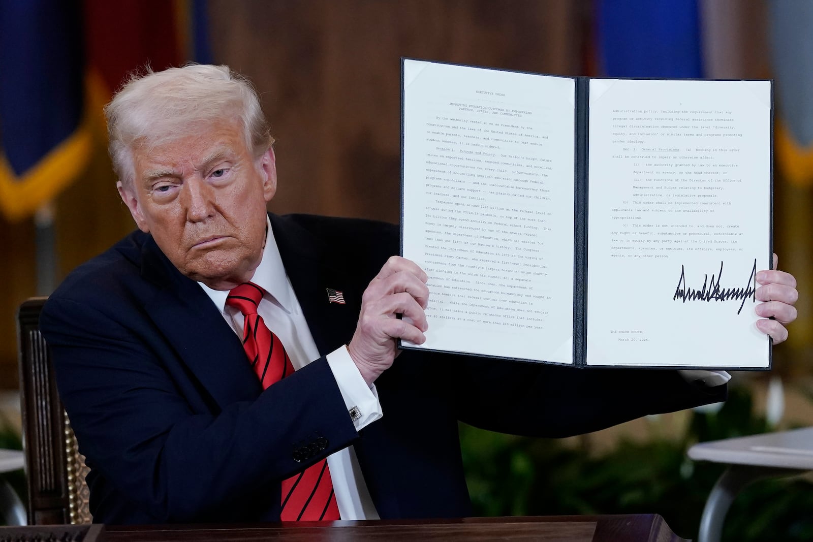 President Donald Trump holds up an executive order in the East Room of the White House in Washington, Thursday, March 20, 2025.(AP Photo/Jose Luis Magana)