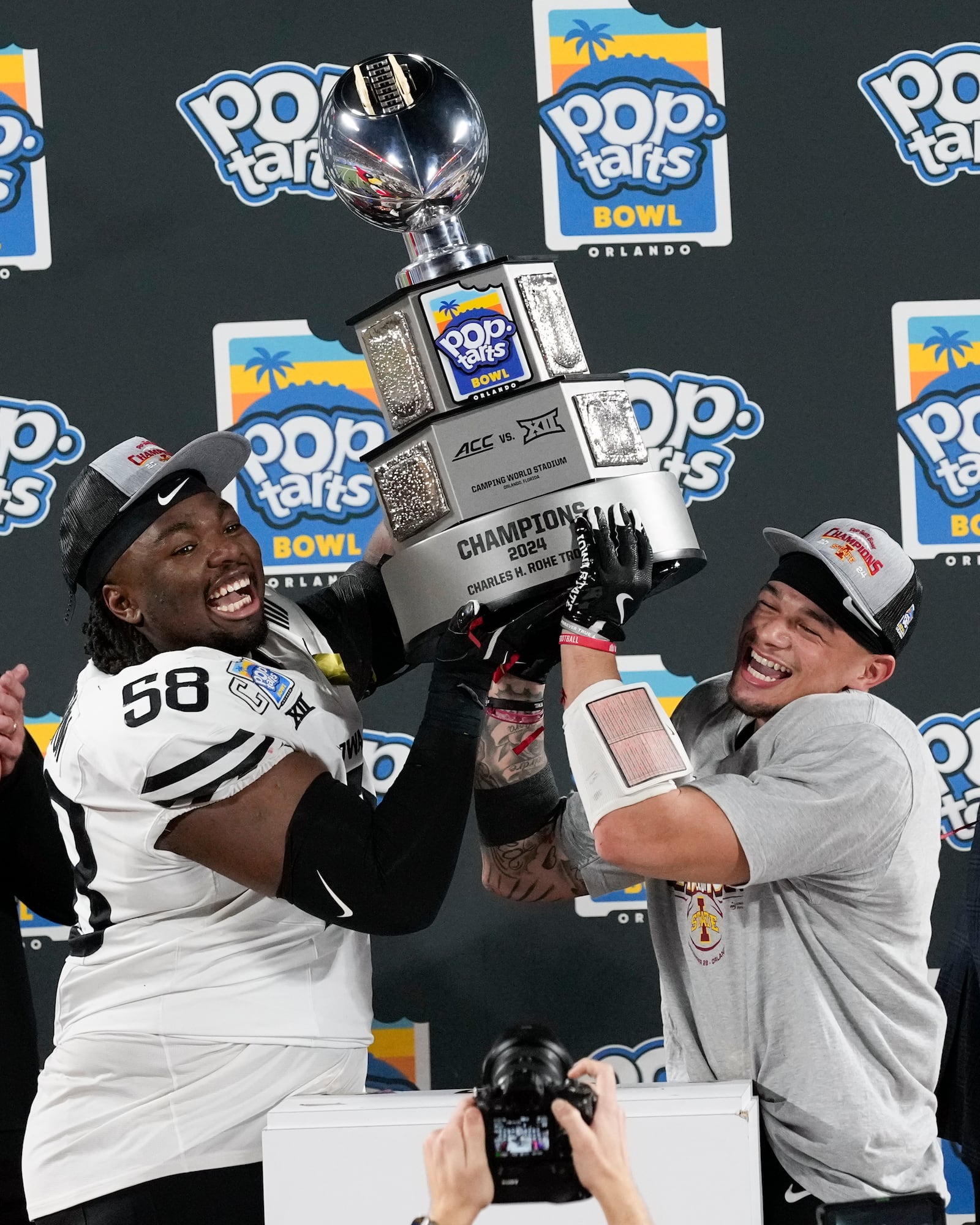 Iowa State defensive lineman J.R. Singleton (58) and wide receiver Jaylin Noel, right, hold up the championship trophy after winning the Pop Tarts Bowl NCAA college football game against Miami, Saturday, Dec. 28, 2024, in Orlando, Fla. (AP Photo/John Raoux)