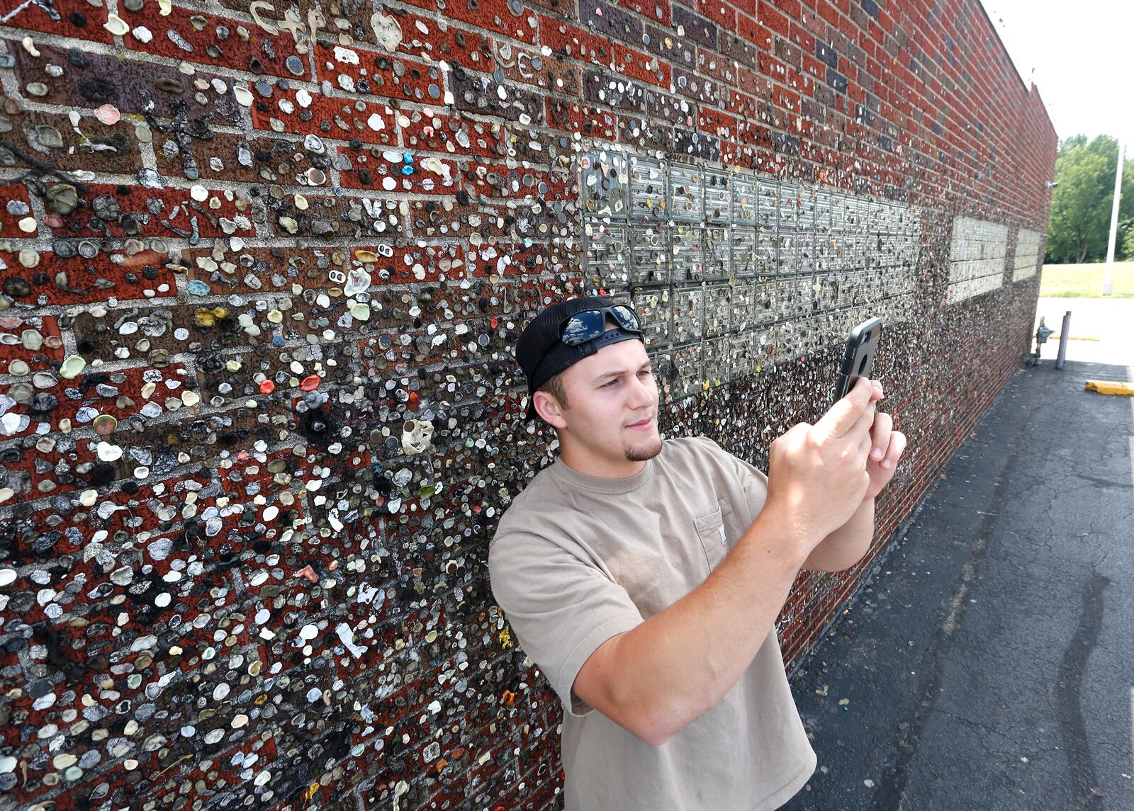 Jeriah Crawley, of Sacremento, Calif., takes a selfie in front of a gum filled wall at the Maid-Rite Sandwich Shoppe in Greenville. The gum sticking tradtion began more than eight decades ago. LISA POWELL / STAFF