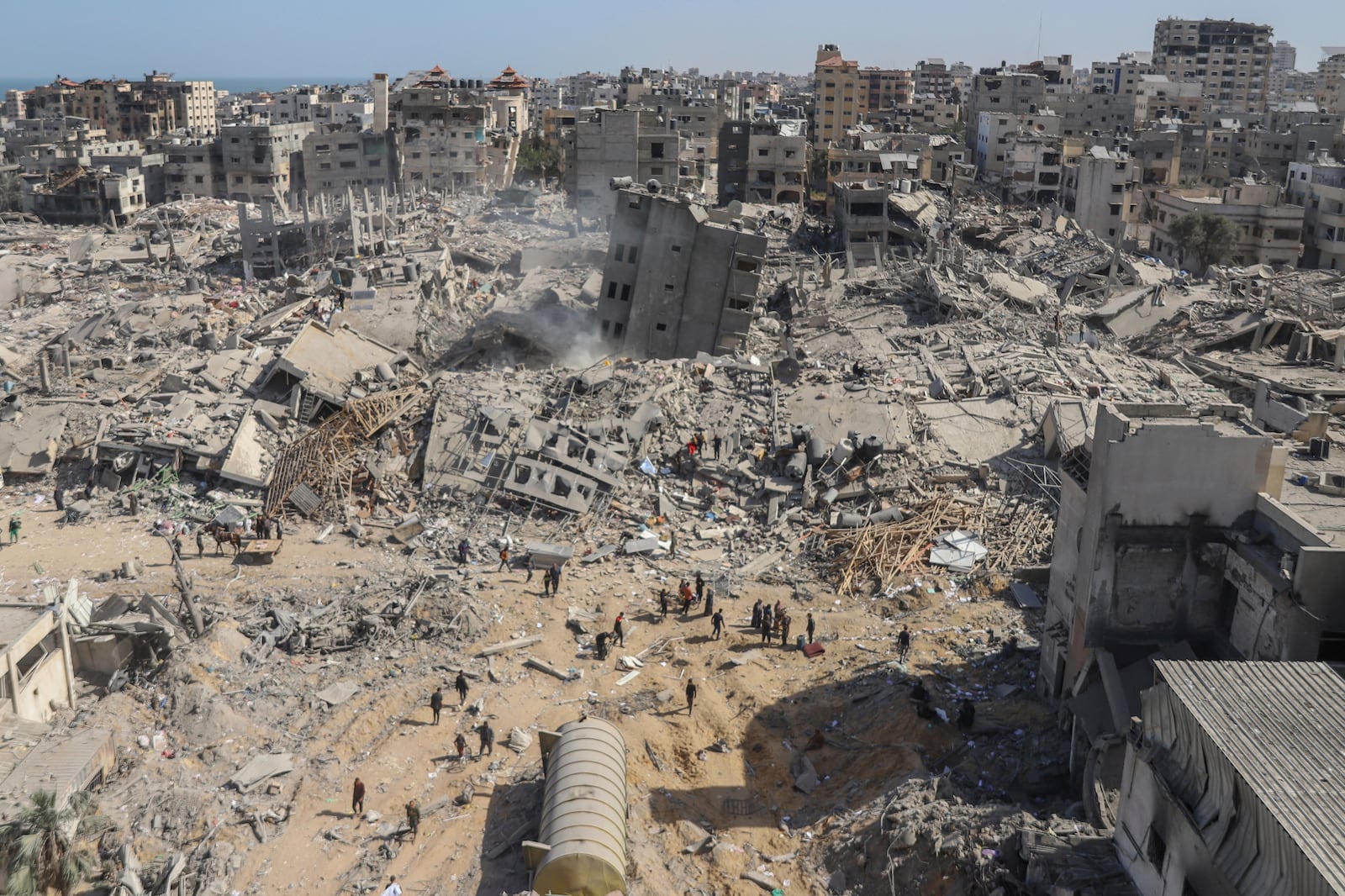 FILE - Palestinians walk through the destruction left by the Israeli air and ground offensive on the Gaza Strip near Shifa Hospital in Gaza City, Monday, April 1, 2024. (AP Photo/Mohammed Hajjar, File)