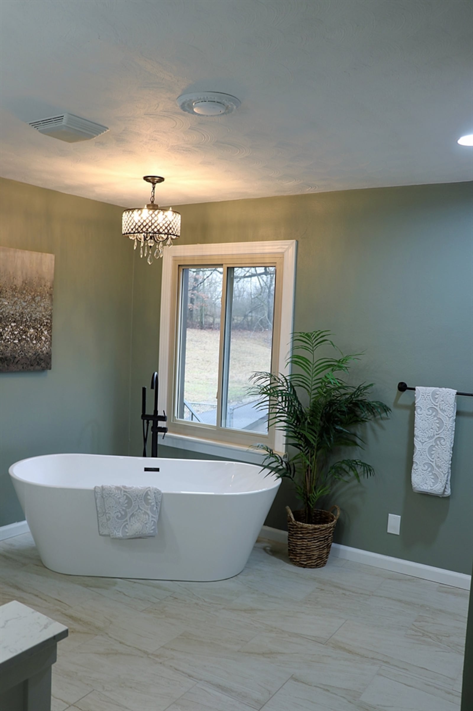 The guest bath has a vanity with two farmhouse sinks, a stand-alone soak tub beneath a window and a walk-in shower with ceramic-tile surround. 